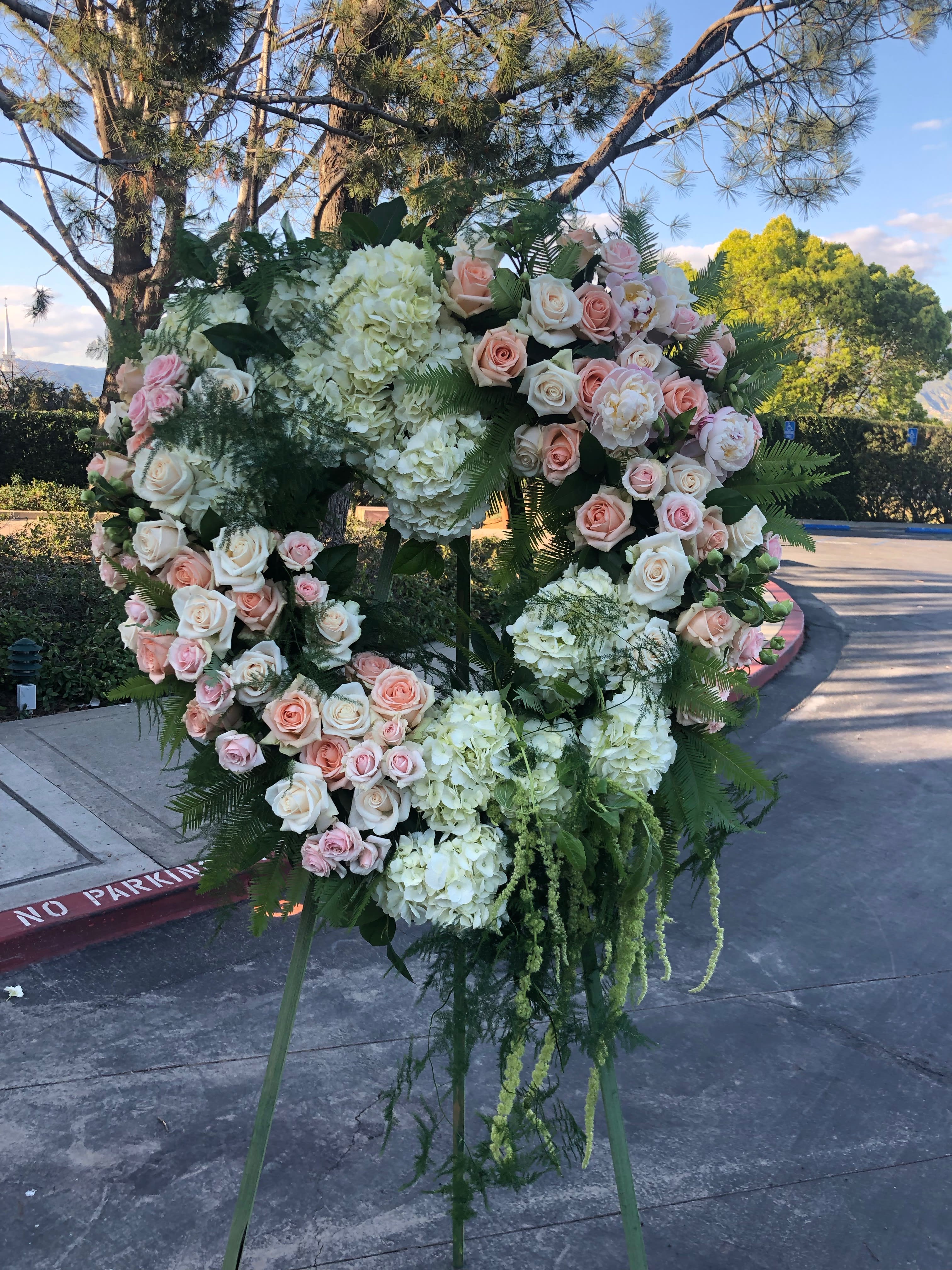 Large floral wreath on an easel with pink and white roses and hydrangeas