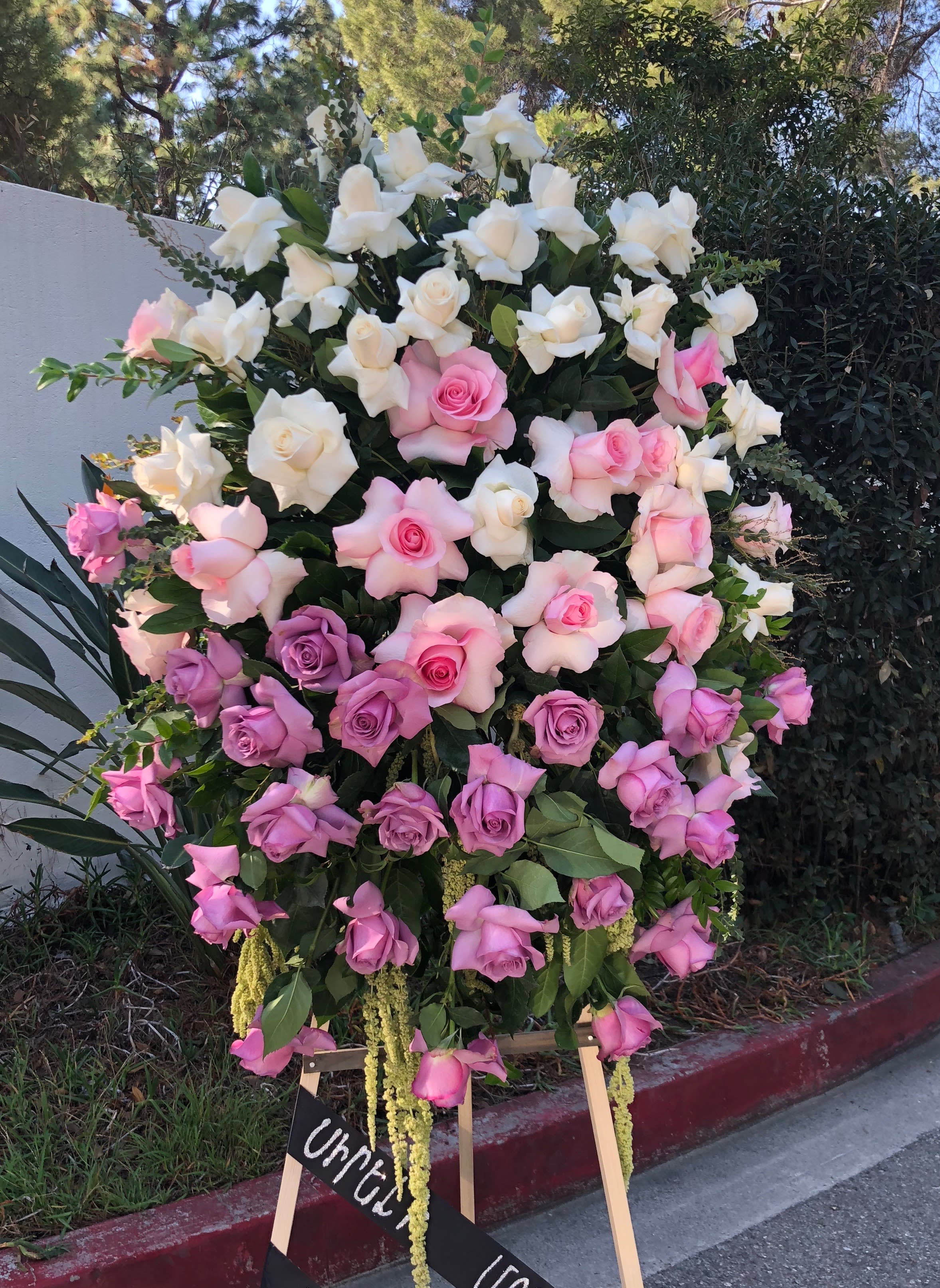 Large standing arrangement of pink, lavender, and white roses
