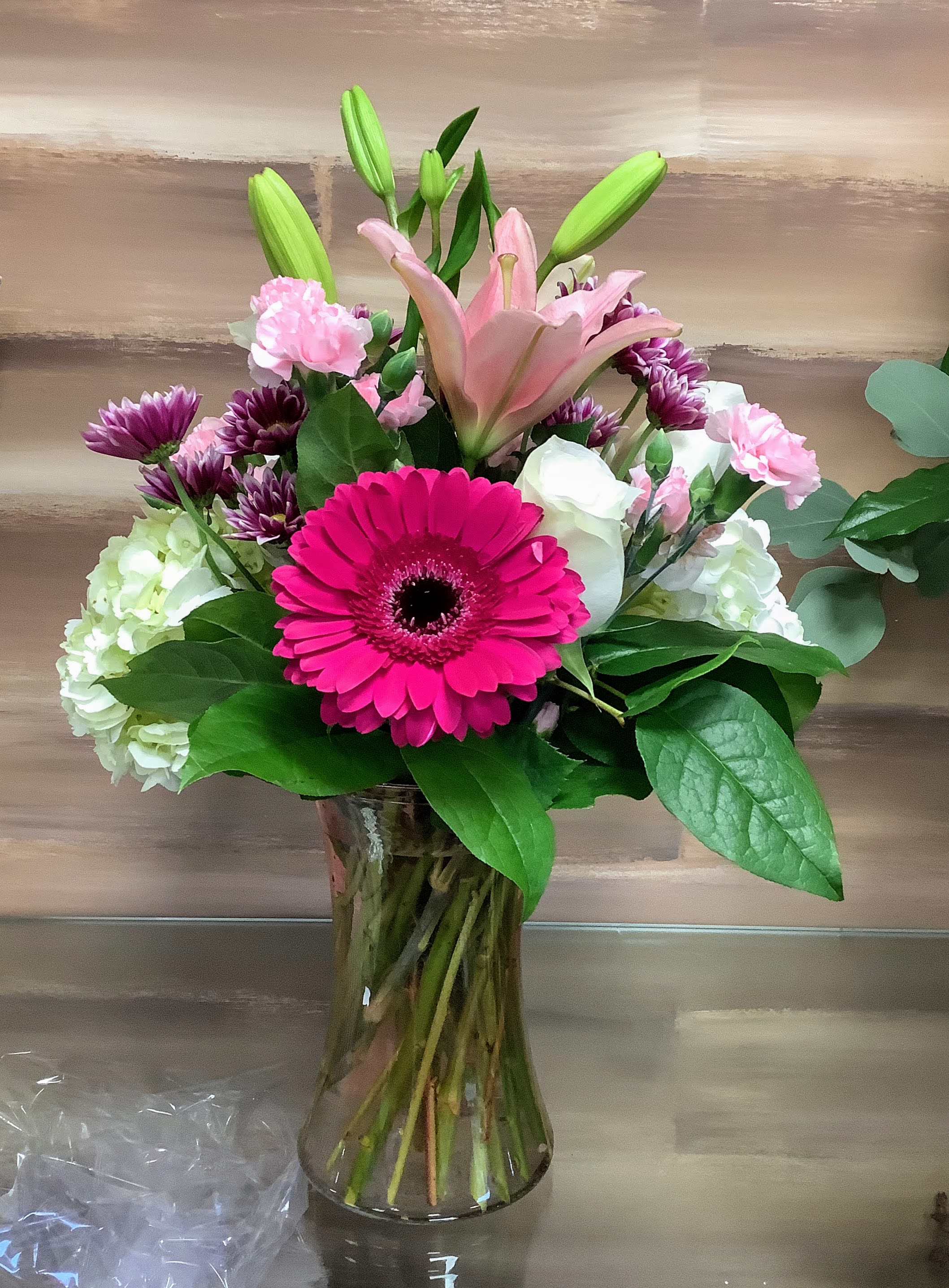 Bouquet of pink lilies, gerbera daisies, and mixed blooms in a glass vase