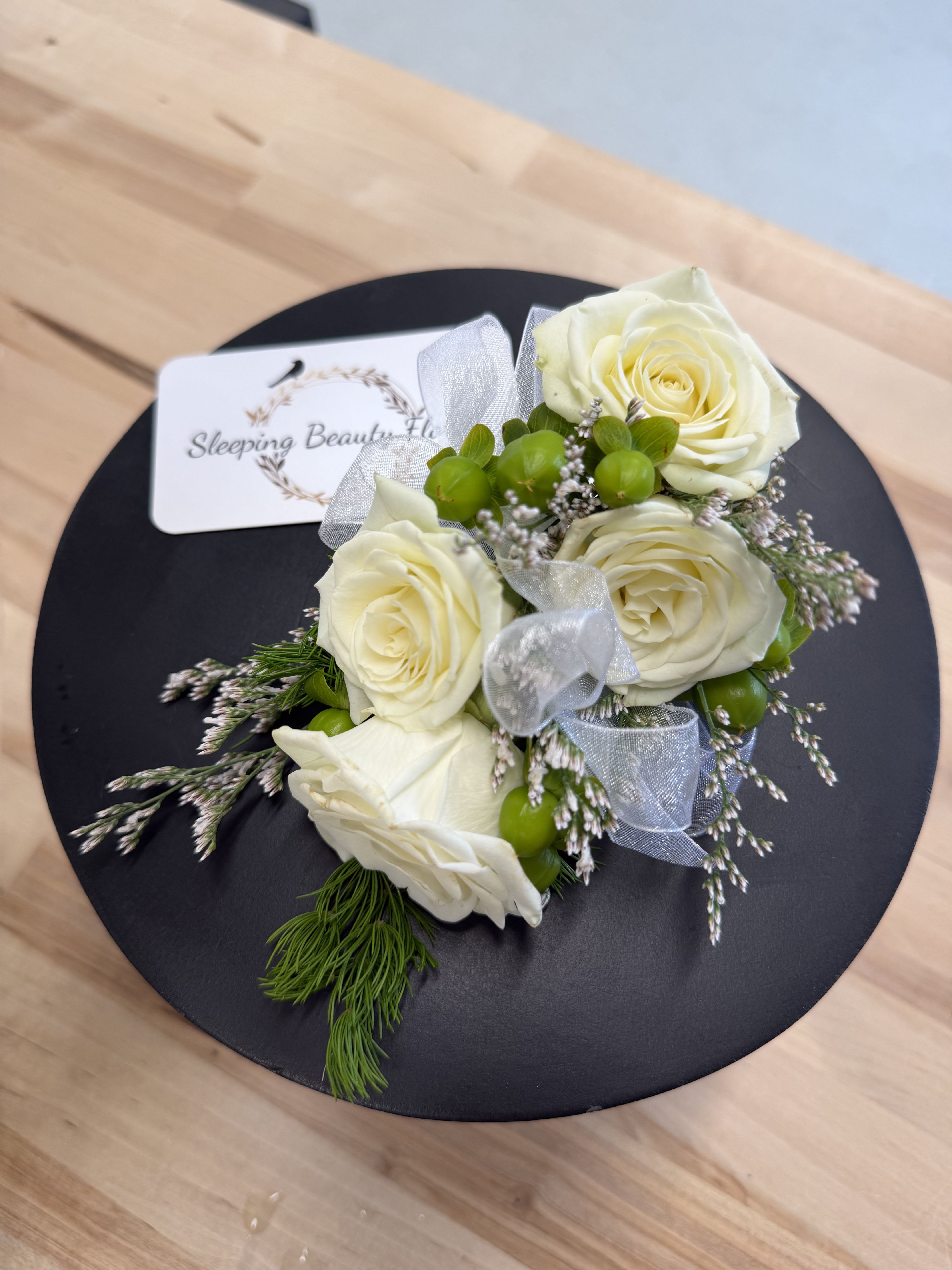 Corsage - Five-spray Rose   - A classic white corsage with silver sheer ribbon, this wrist arrangement looks good with any outfit. A perfect compliment to any prom, formal, or wedding event.   Please note your ribbon color preference