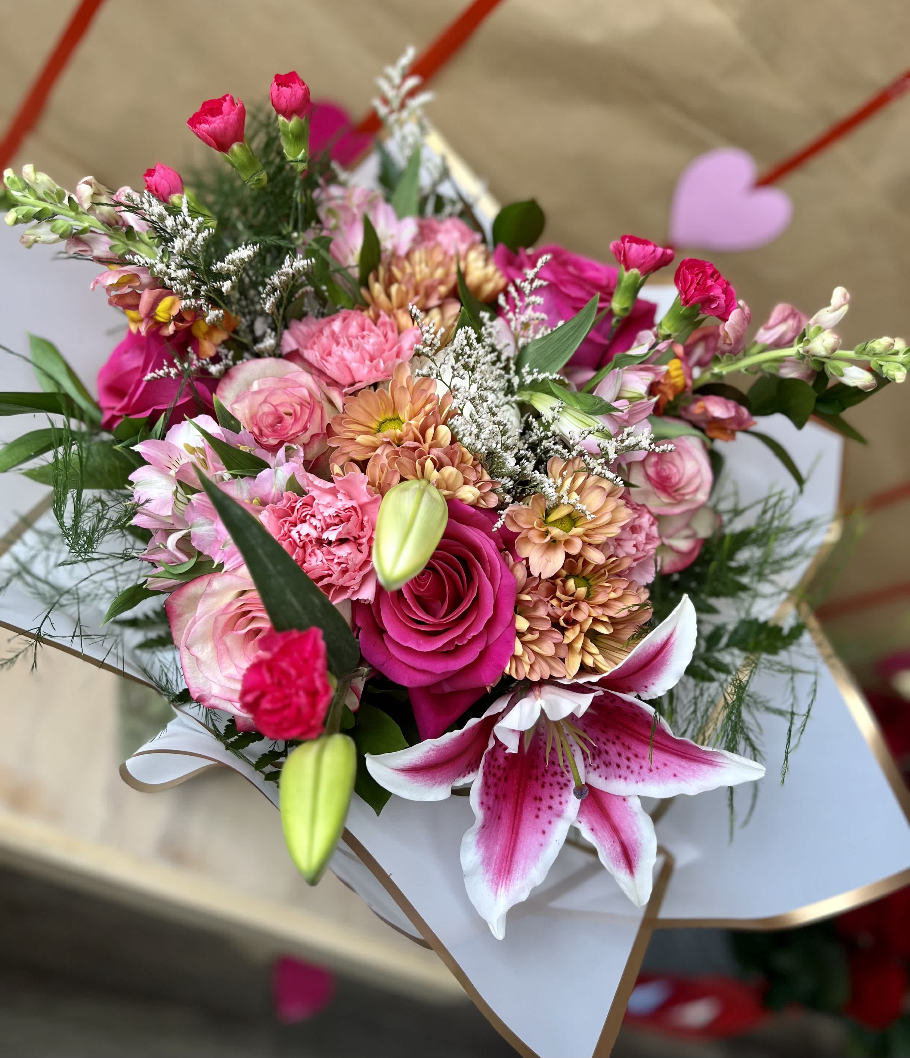 Pink mixed bouquet with roses, lilies, and chrysanthemums in white wrap