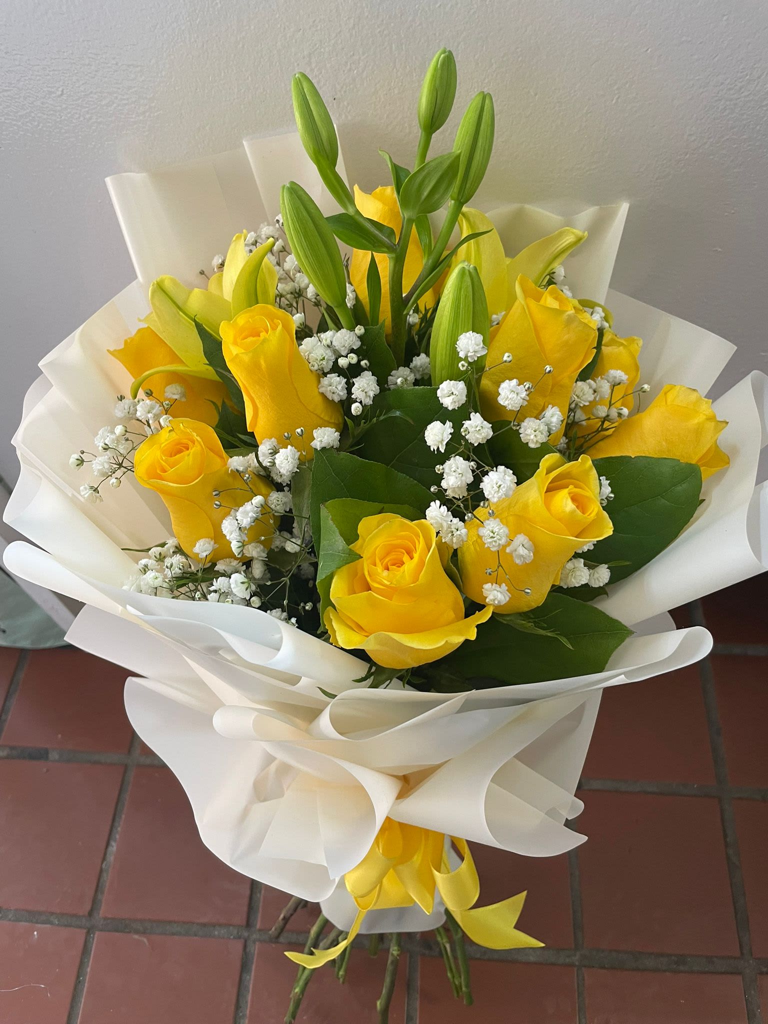 Yellow roses and lily buds wrapped in white paper
