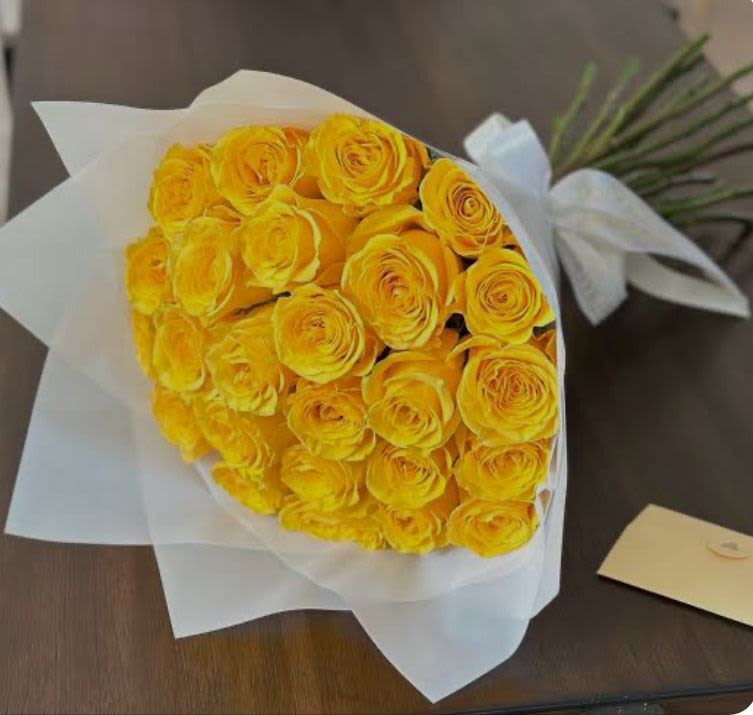 Bouquet of yellow roses wrapped in white paper