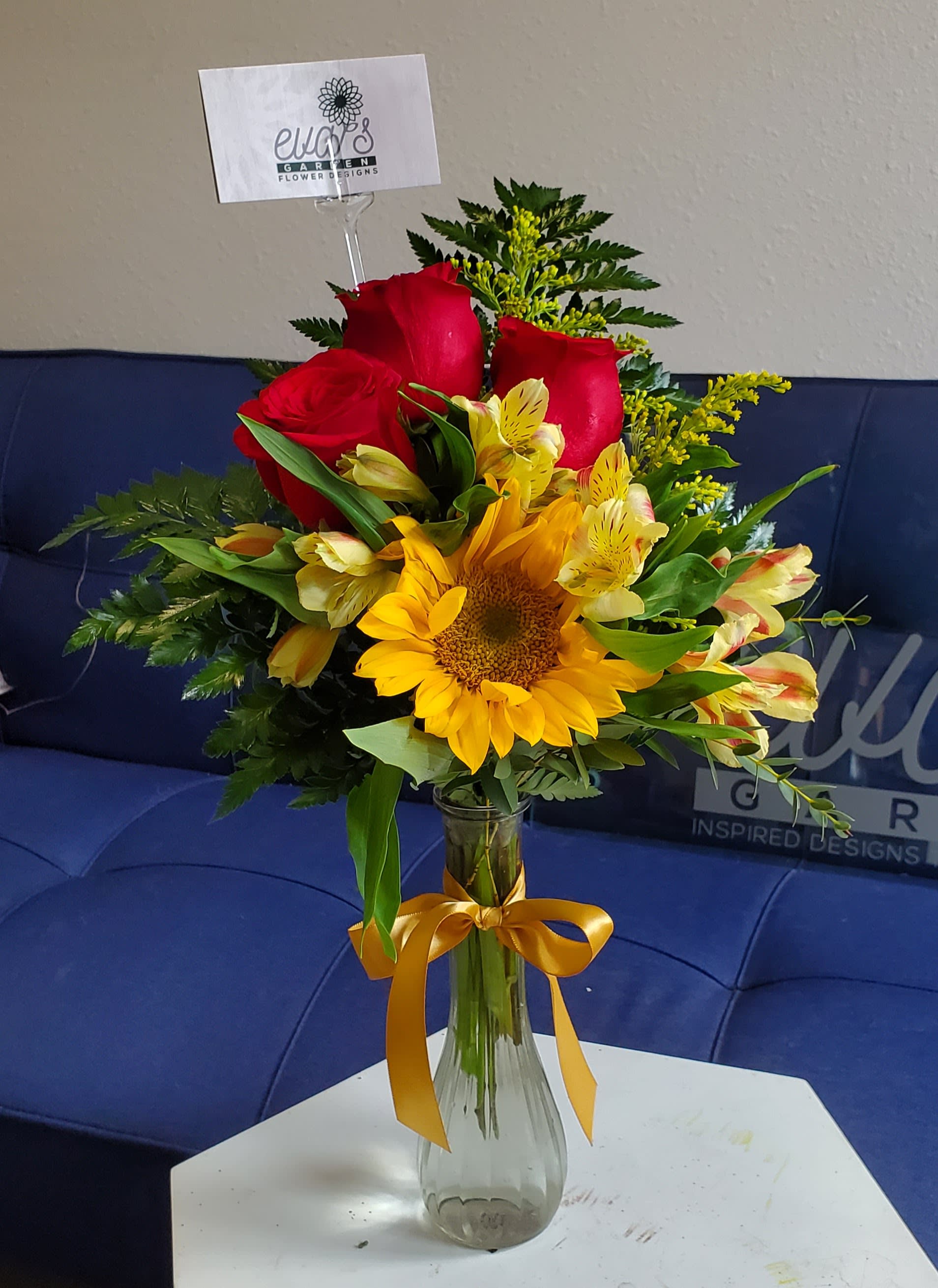 Bouquet of red roses and yellow flowers in a glass vase with a ribbon