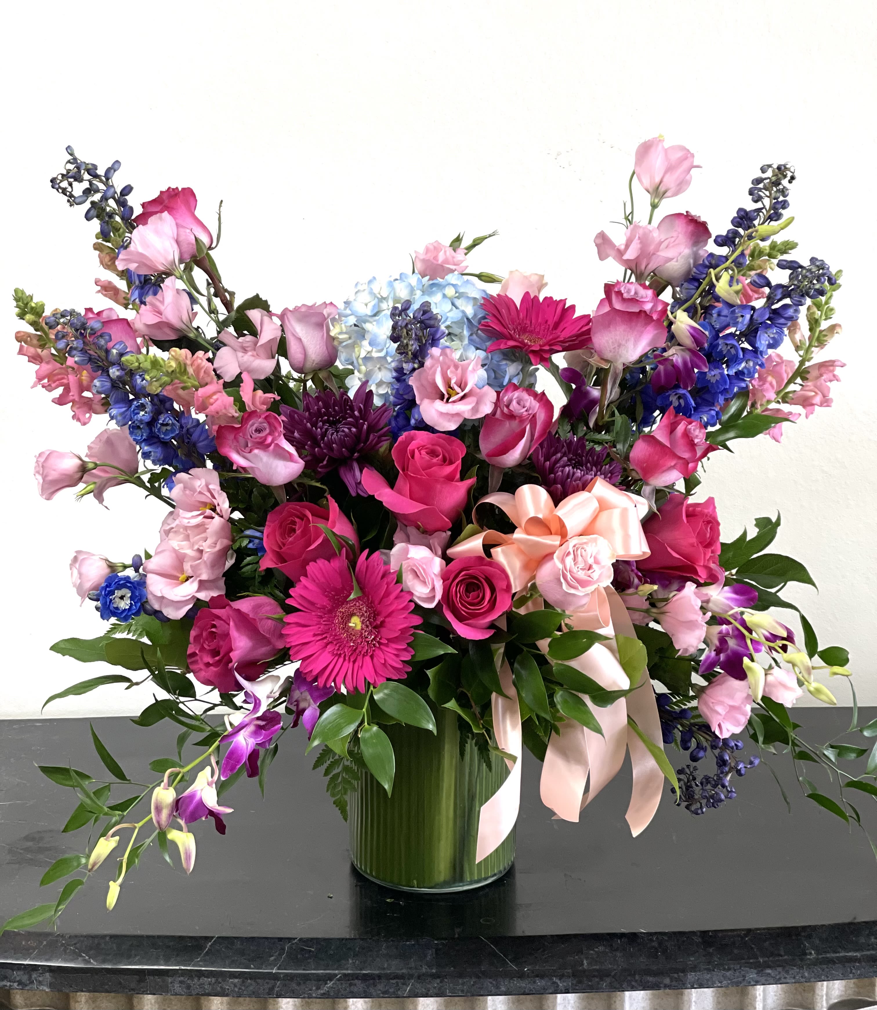 Large mixed bouquet of pink, purple, and blue flowers in a glass vase