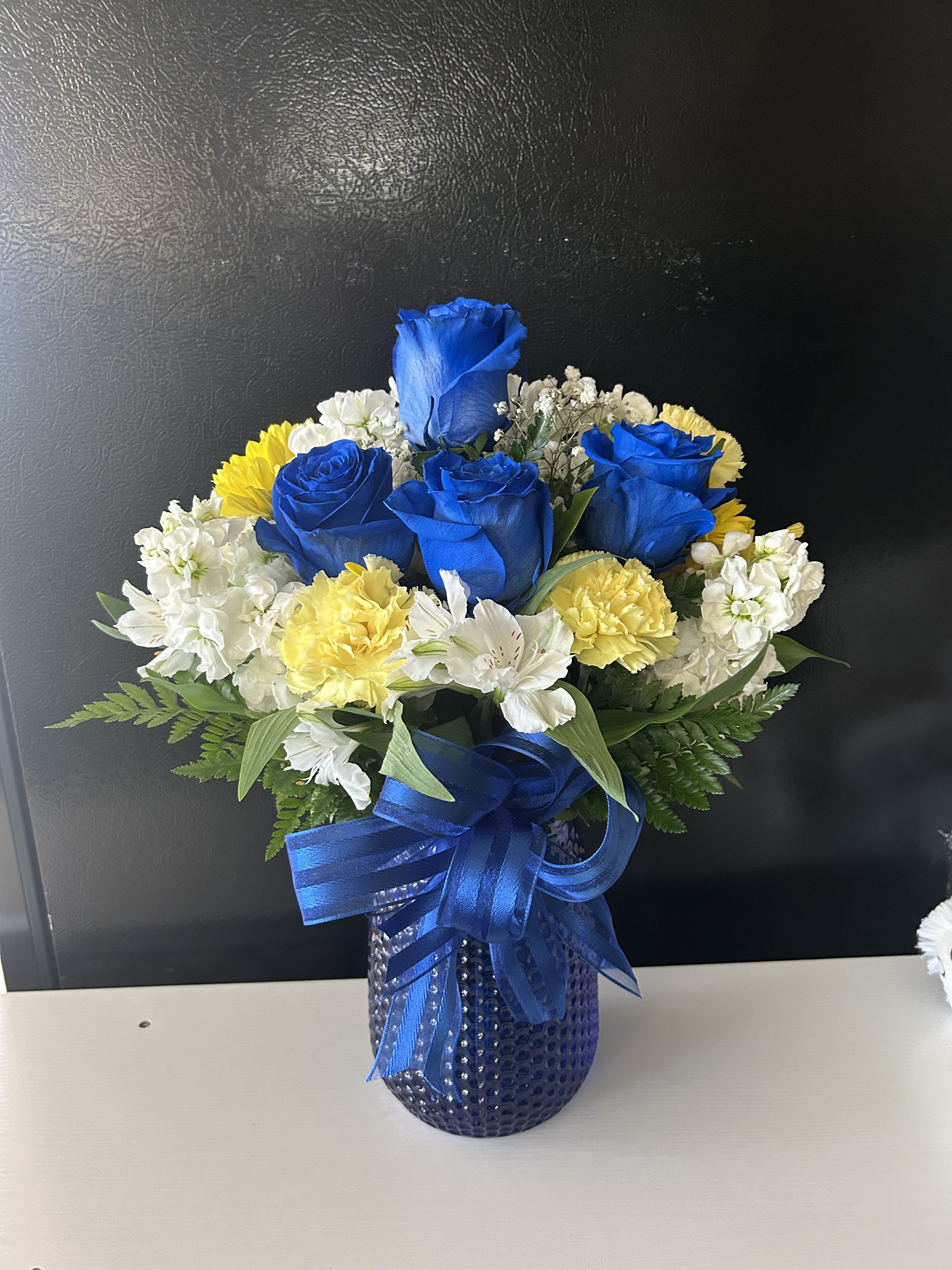 Blue roses with white and yellow flowers in a blue vase