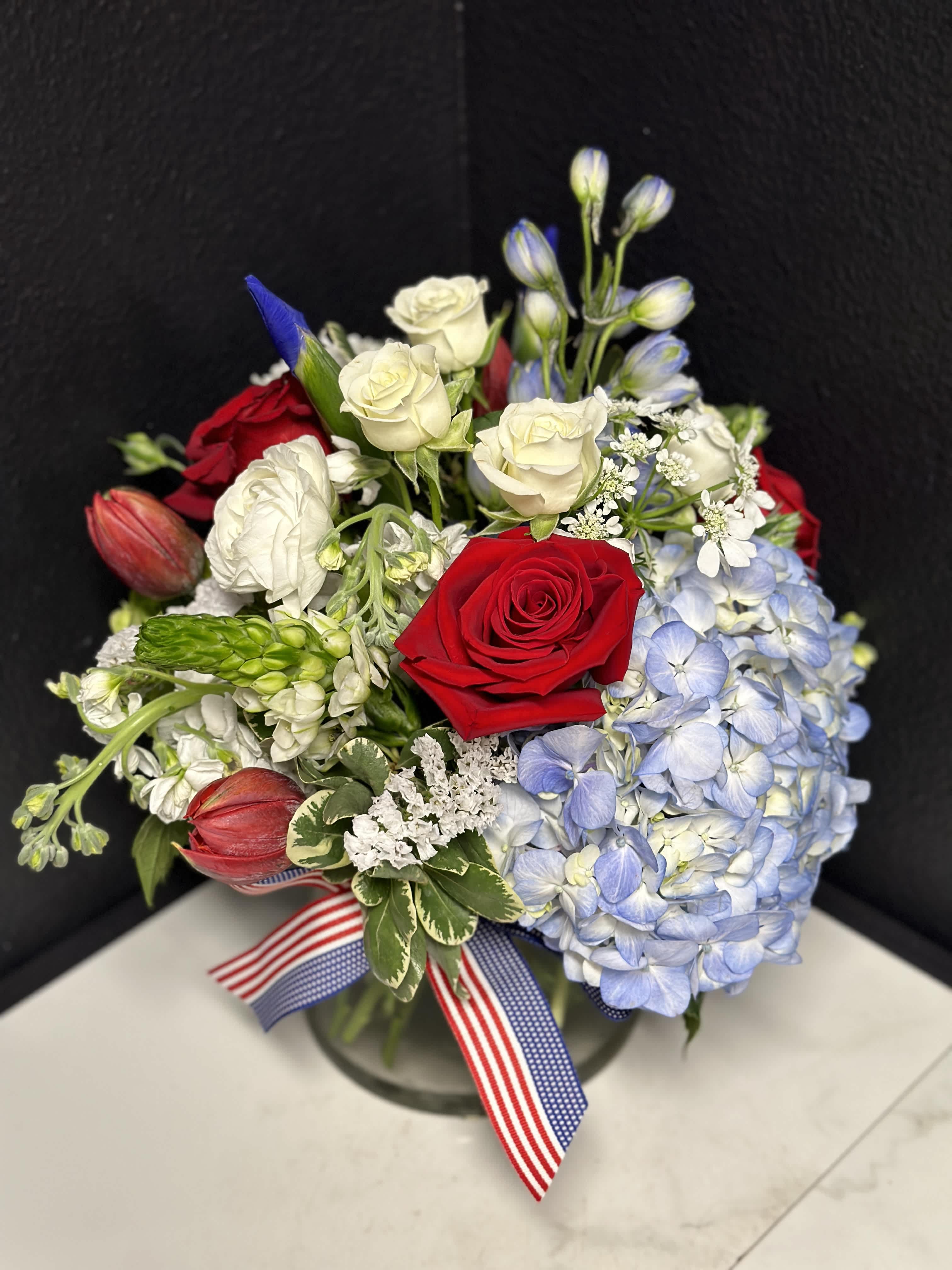 Bouquet of red and white roses with blue hydrangea in a glass vase