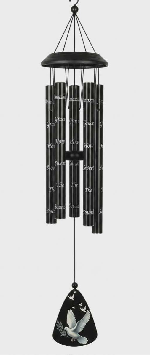 30" Amazing Grace White Dove Wind Chime - A black 30" memorial wind chime designed for sympathy and remembrance makes a thoughtful gift to honor a departed loved one. This condolence wind chime features printed words like "Amazing," "Grace," "How," and "Sweet" across its metal tubes and a white dove pendant at the base-symbols that read as reverent and comforting for a funeral, graveside tribute, or a quiet moment of reflection.  The piece is crafted with multiple black metal tubes suspended from a circular top frame; gentle breezes set the tubes singing to create a peaceful, contemplative sound. A hanging cord allows easy placement from a tree branch, porch, or memorial hook, and the included metal easel stand provides a clean, upright display option for indoor settings or at a service. The monochrome palette and religious wording give this piece a solemn, respectful presence that pairs naturally with white lilies, roses, or other sympathy flowers if you choose to add a floral tribute.  Choose this wind chime to send a message of comfort-the dove and the words offer reassurance and memory for the person you're honoring. The 30" size makes it visible without overpowering a memorial setting; 