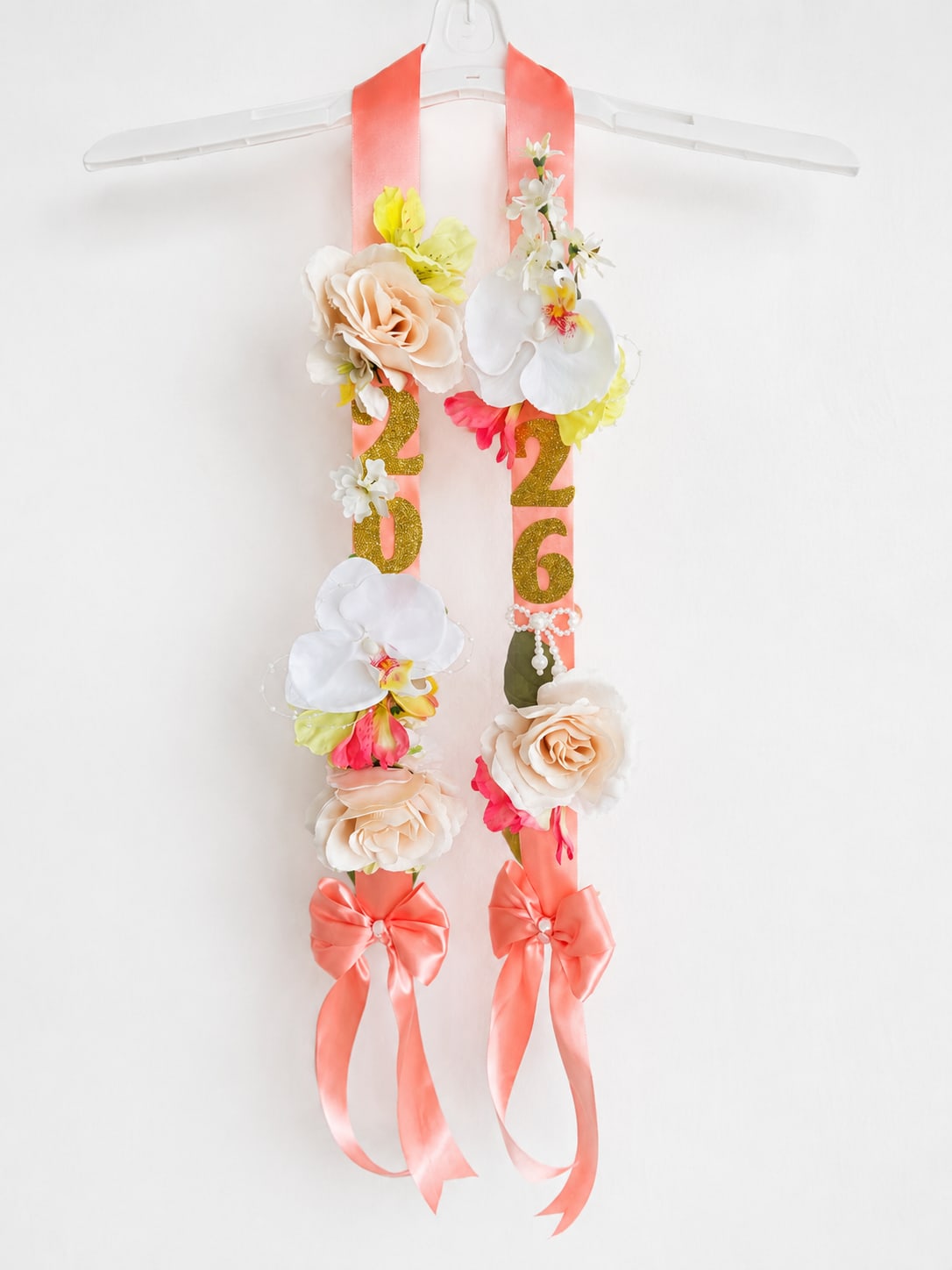 Coral &amp; Gold 2026 Ribbon Lei - Soft coral satin ribbon lei with glittering gold “2026” numbers, using SILK ivory roses, orchid accents, and elegant satin bows. This handcrafted graduation piece combines classy floral details with a modern, feminine look — perfect for celebrating your graduate’s big achievement and creating memorable photos. 27in long
