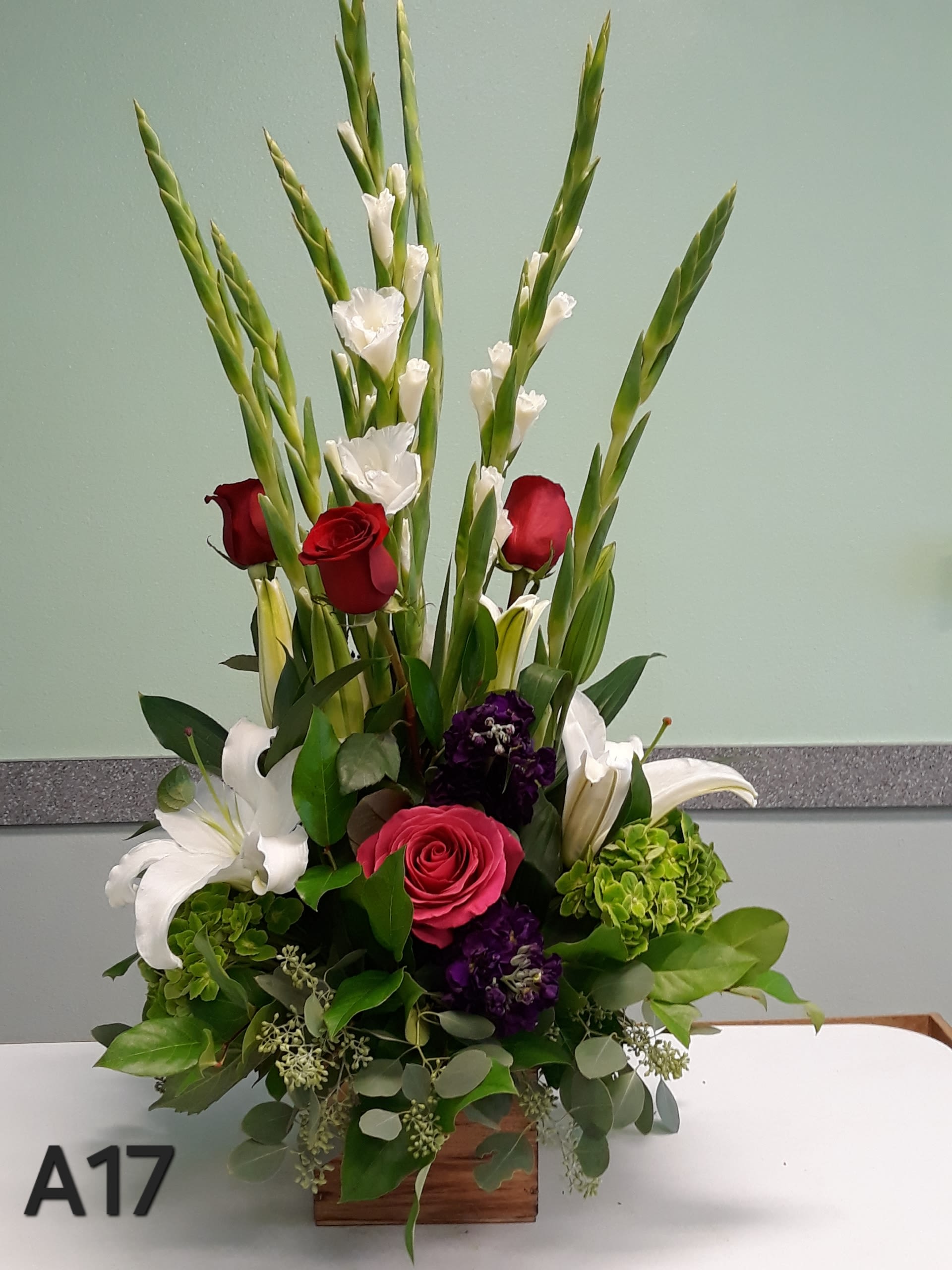 A17 - It has red rose, white gladiolus, green hydrangea, white lily, and purple stock