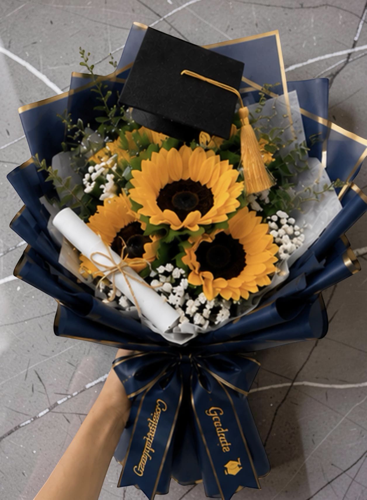     Classic Sunflower Wrap - A cluster of big, golden sunflowers makes an immediate, joyful statement-this sunflower arrangement is ideal as a birthday bouquet, a congratulations gift, or a thoughtful just-because surprise. The bright yellow blooms sit against deep navy wrapping for a bold yellow-and-blue contrast that reads both celebratory and slightly formal, so the person you're honoring will feel truly noticed and celebrated.  Several sunflowers are tightly grouped with small white filler flowers and airy green foliage woven through the heads for texture and movement. The stems are finished in decorative deep navy paper with gold edging and a wide satin ribbon in a matching shade, giving the bouquet a polished presentation that arrives ready to set on a table or bedside. Recommend keeping stems in fresh water, trimming ends before arranging, and displaying away from direct heat to prolong bloom life.