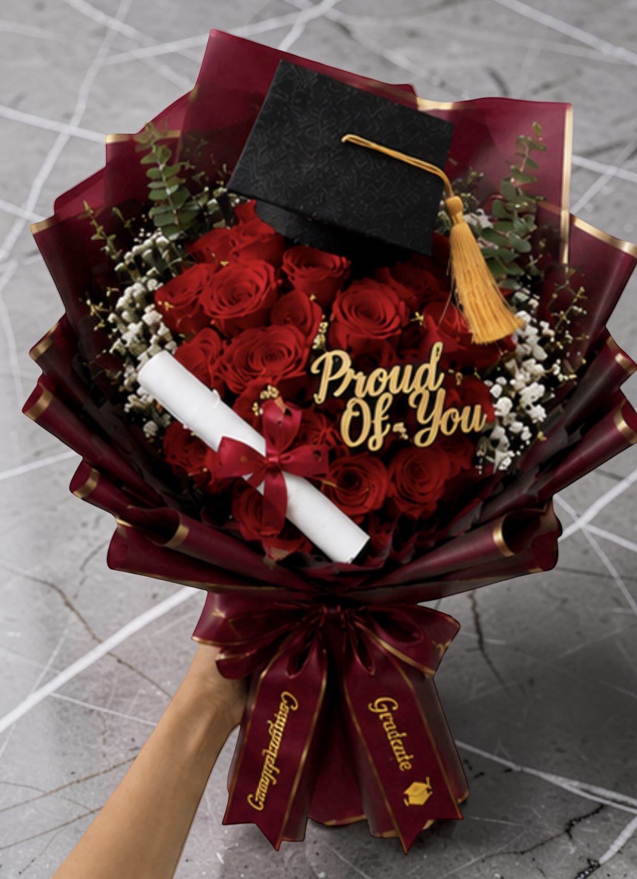 Graduation Bouquets  - A bold cluster of roses made for celebration-these graduation bouquets pair classic red and vivid hot-pink roses with academic accents to create an unforgettable congratulatory gift. Perfect as a graduation bouquet or commencement gift, each hand-held arrangement is finished with a miniature graduation cap, a rolled diploma scroll, and decorative tassels so the person you're celebrating will feel recognized and honored the moment they see it.  Choose from dramatic red bouquets wrapped in deep burgundy or black paper with gold trim, or bright pink versions wrapped in translucent pink paper or black paper with white inner layers for high-contrast flair. All designs feature tightly packed roses surrounded by white filler blooms and eucalyptus-like greenery, plus gold or pink ribbons, decorative bows, butterfly accents, and a keepsake wooden topper or gift tag. The arrangements are carefully wrapped in decorative paper-black wrapping or black-and-gold for a formal look, pink translucent for a cheerful finish-and include a diploma scroll and tassel as shown.  These bouquets are ideal for graduates, proud family members, or friends marking a milestone; they read as both celebratory and thoughtful, the kind of gift that makes someone feel truly seen. Sizes and final styling vary slightly by selection-please choose your preferred color and wrapping when ordering to ensure the exact look you want.