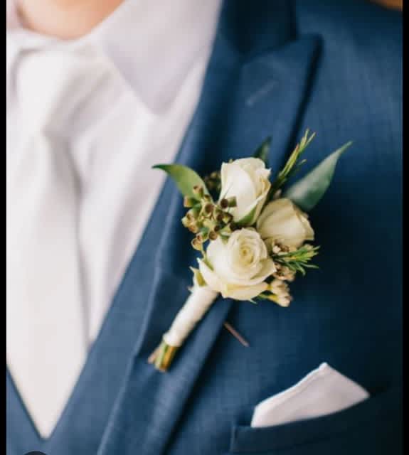 White rose boutonniere pinned to a blue suit jacket