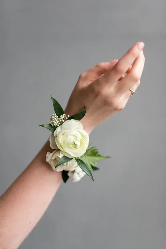 White floral wrist corsage on a person's wrist