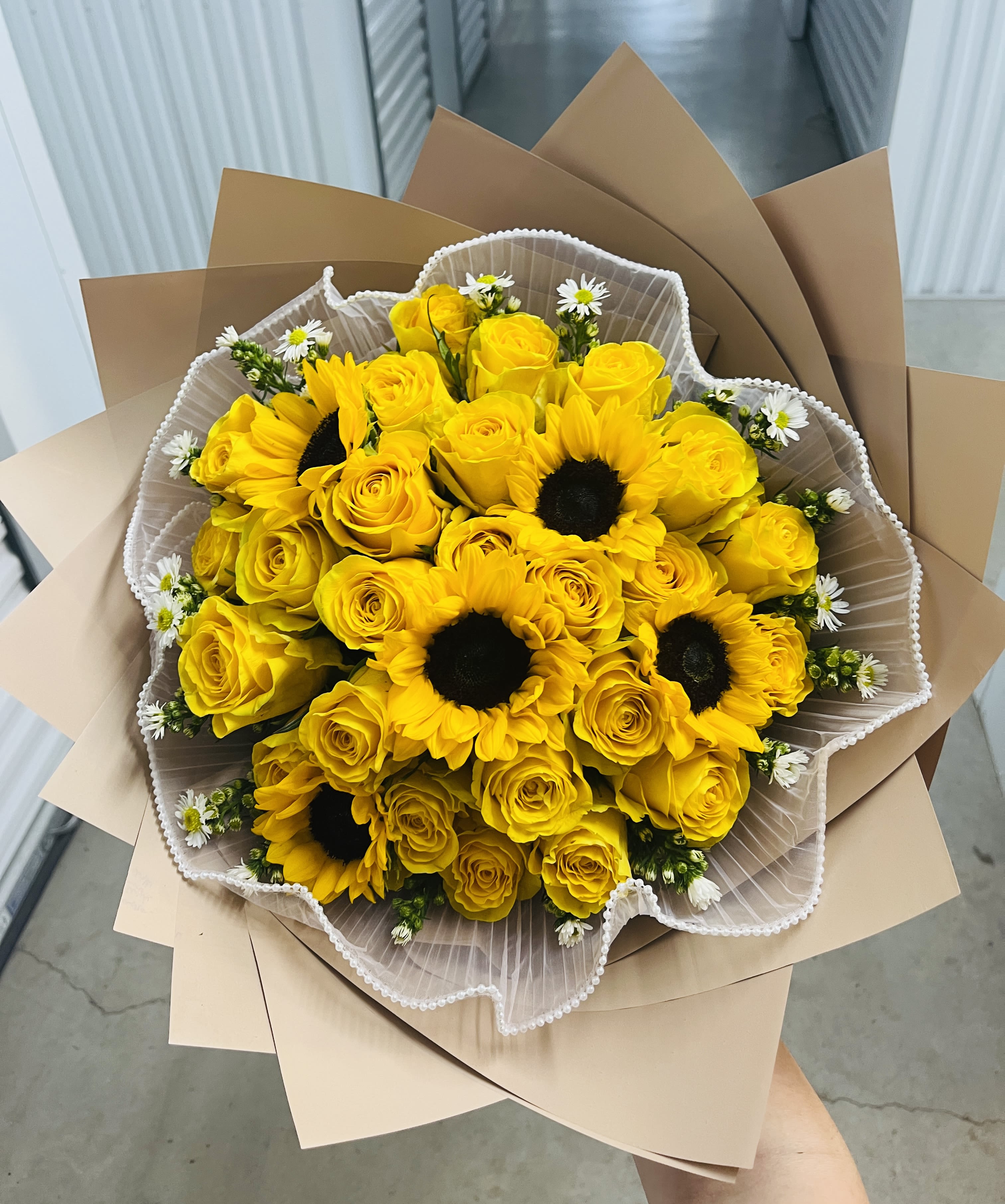 Bouquet of yellow roses and sunflowers wrapped in brown paper