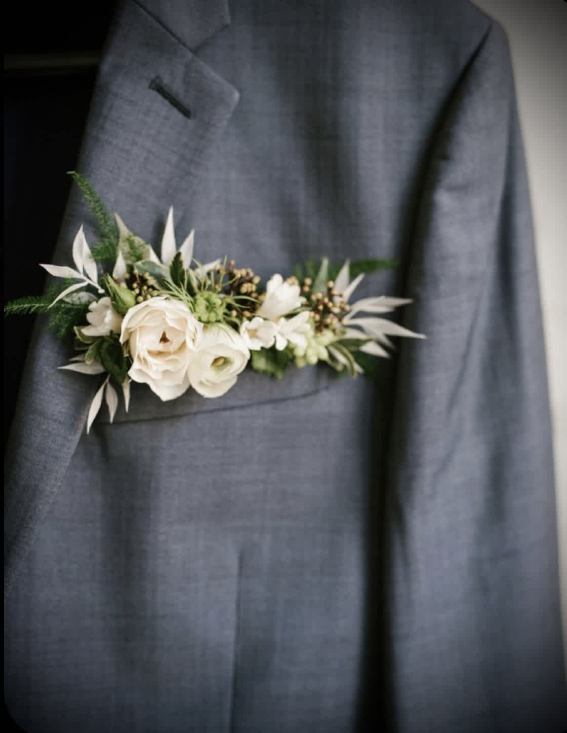 White floral boutonniere pinned to a gray suit jacket