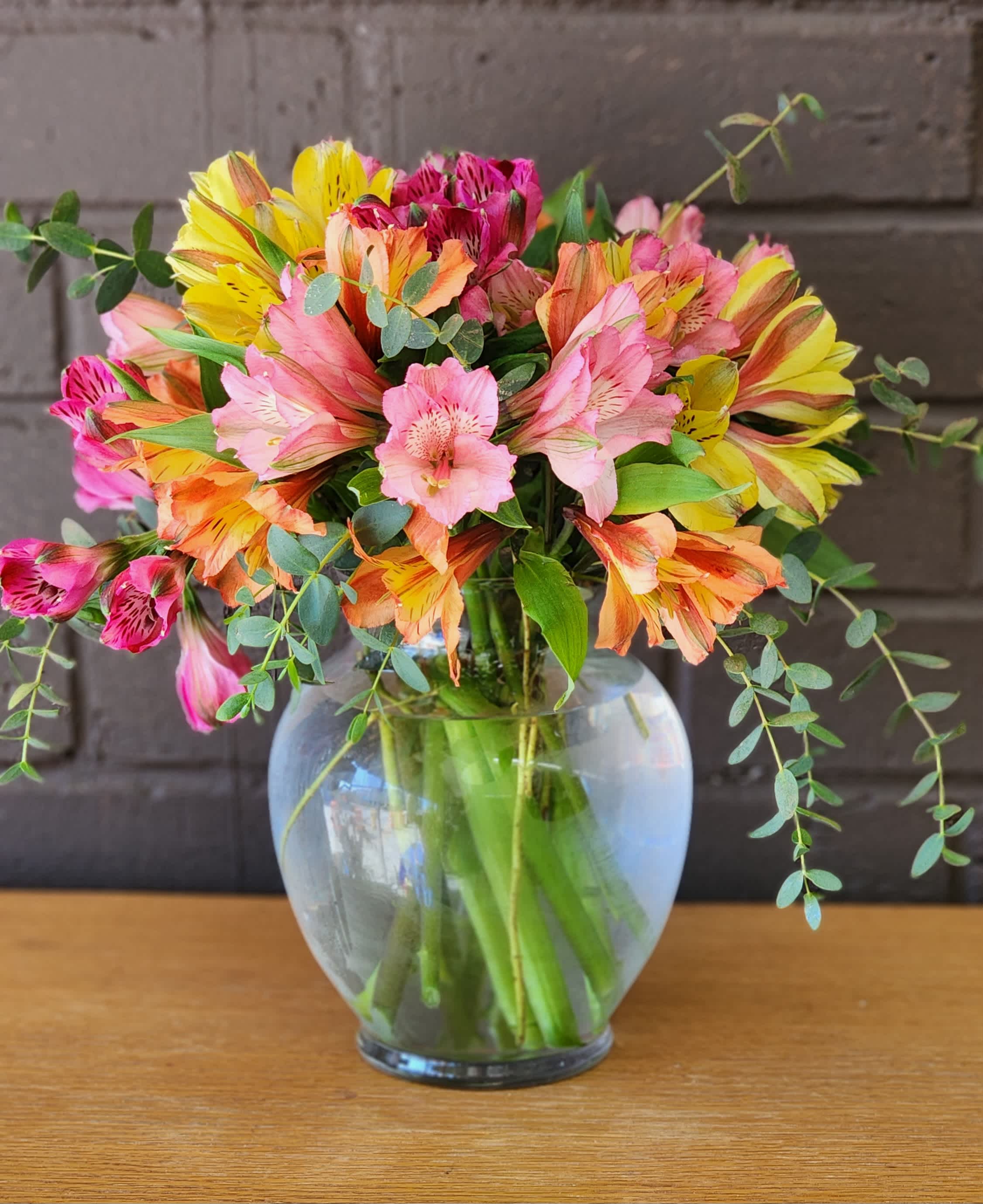 Bouquet of pink, yellow, and orange alstroemeria in a glass vase
