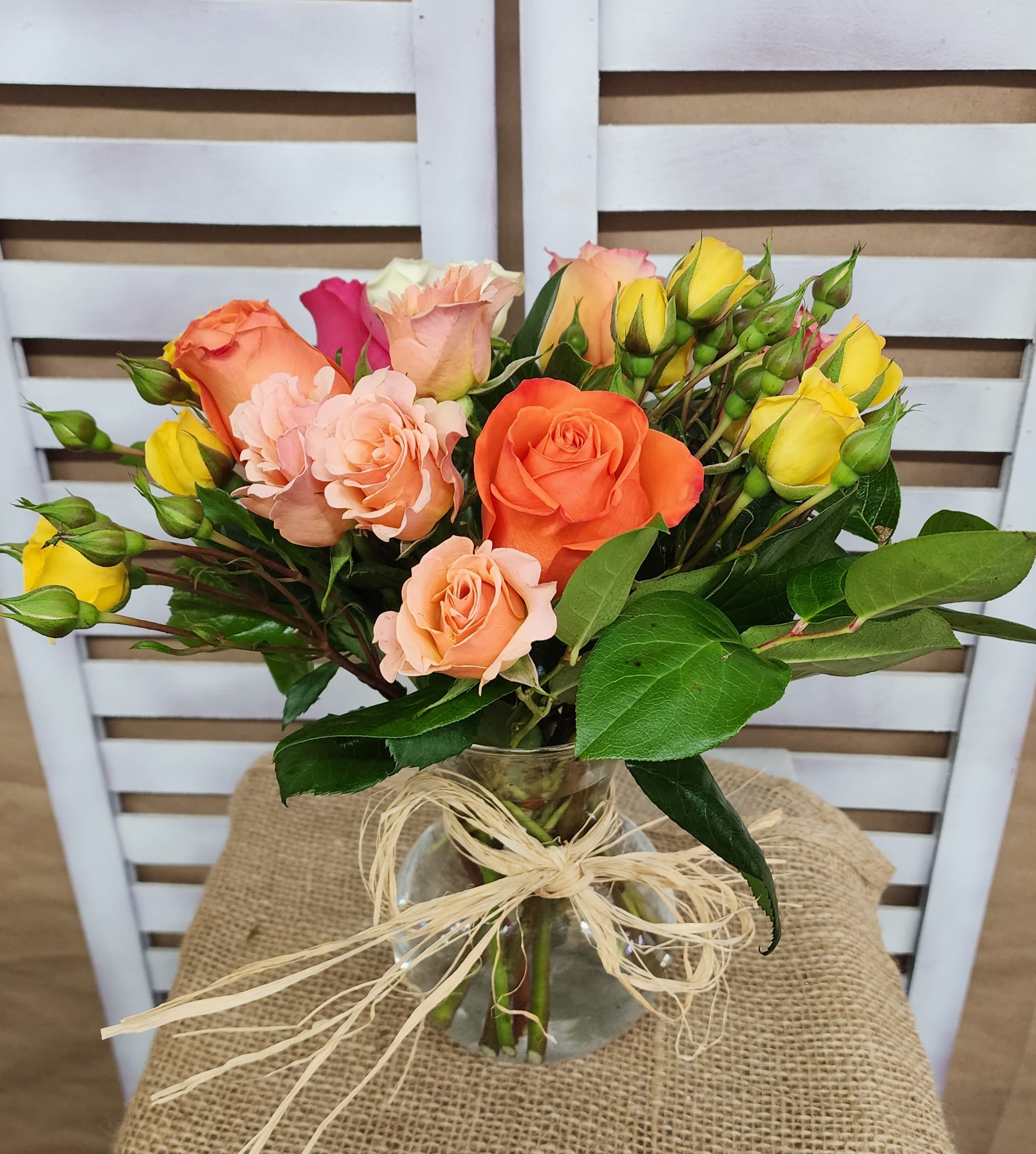 Bouquet of orange, peach, and yellow roses in a glass vase