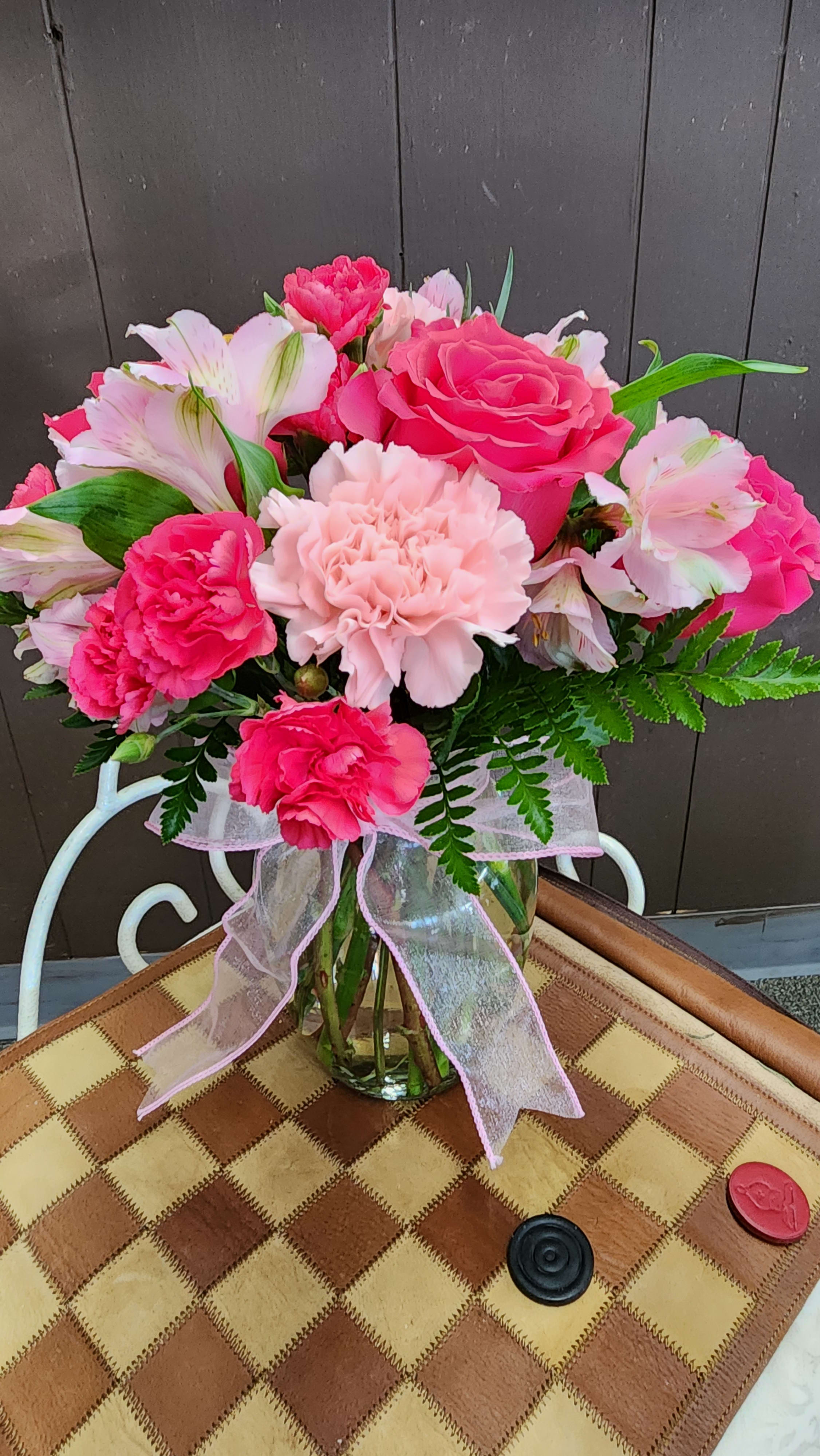 Pink and white flower bouquet in a glass vase with a ribbon