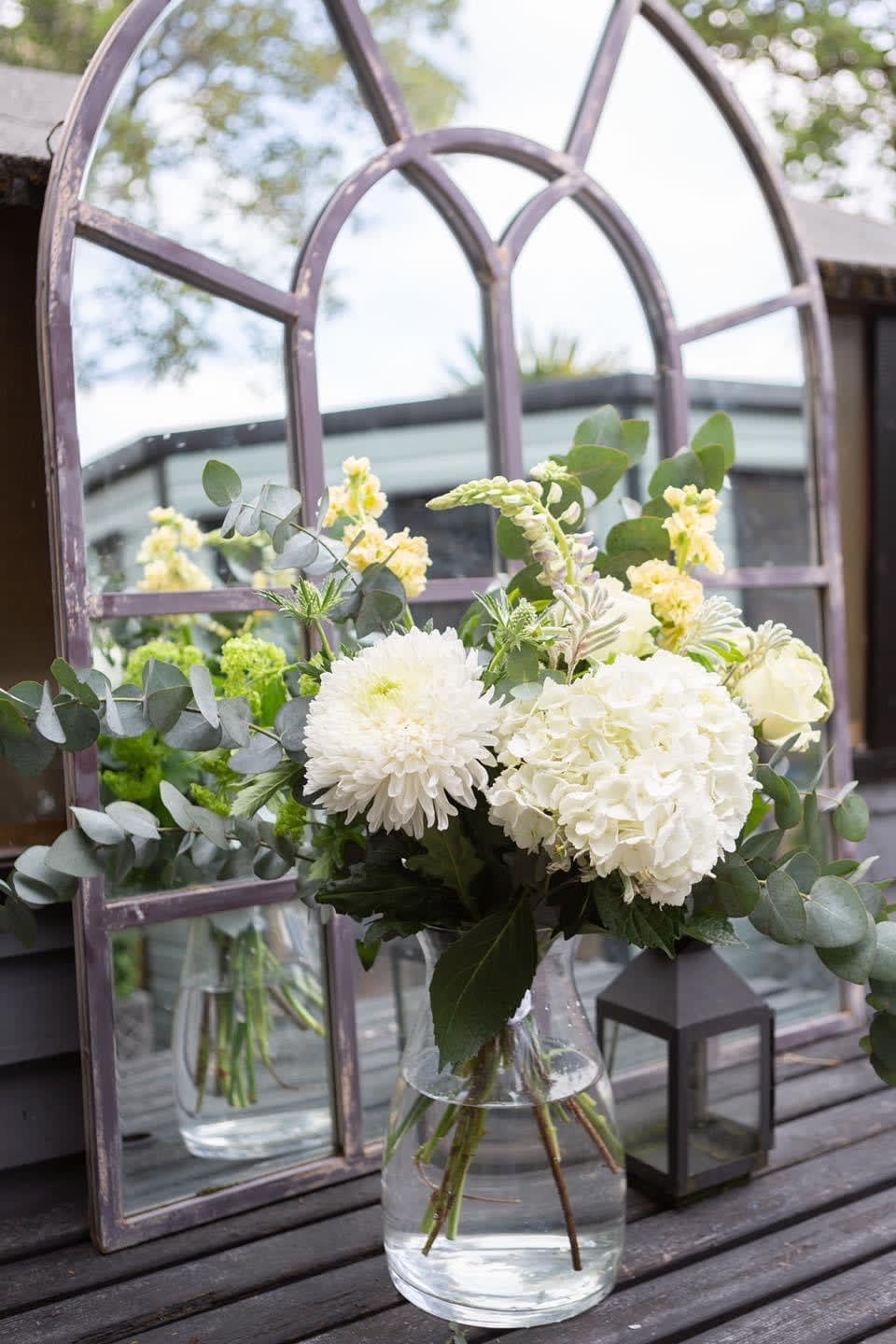White flowers in a clear glass vase with eucalyptus
