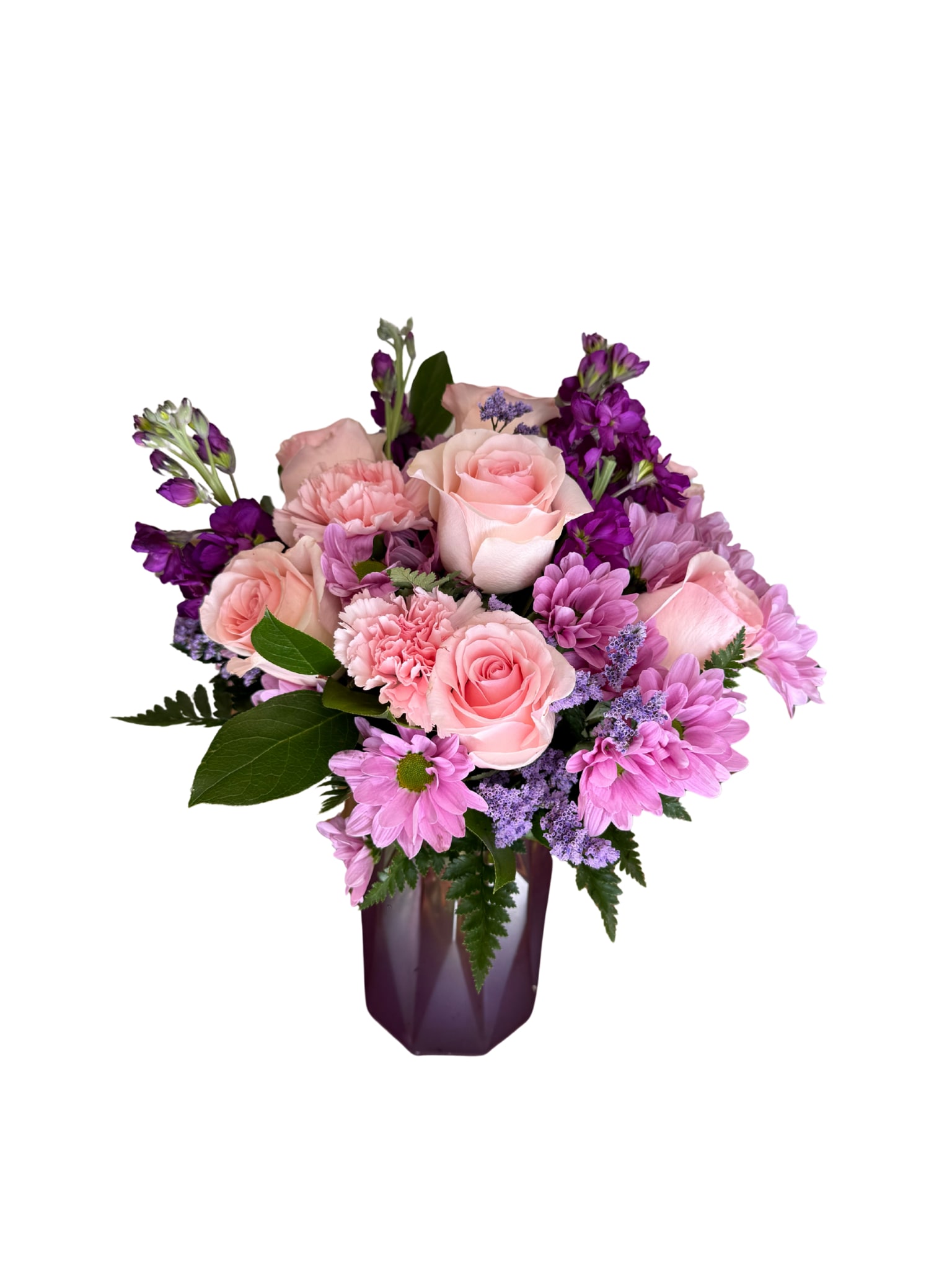 Always with me bouquet - Lavender chrysanthemums and blush pink roses mingle with pink carnations and deep purple stock to create a romantic, cheerful flower arrangement perfect for a birthday, anniversary, or a "thinking of you" moment for mom. This flower arrangement for Mom is designed to make her feel seen and cherished-soft pastels balanced with saturated purples give it a tender, slightly formal presence that reads both celebratory and comforting.  The compact, rounded bouquet features stock for height and fragrance, roses and carnations for texture, and small filler blooms to soften the silhouette. Colors run from blush pink and creamy white to lavender and rich purple, all gathered in a faceted dark purple glass vase that lifts the blooms and adds a polished, gift-ready finish. Sized to sit beautifully on a table or bedside dresser, it's the kind of bouquet that feels thoughtfully arranged and instantly uplifting.  Ideal for Mother's Day, a milestone, or simply to say you're thinking of her, this arrangement sends a message of appreciation and warmth that will brighten her room and her day. Arrange for local delivery or pickup and include a short note to make the sentiment personal; light trimming of stems and fresh water will keep the flowers looking their best.