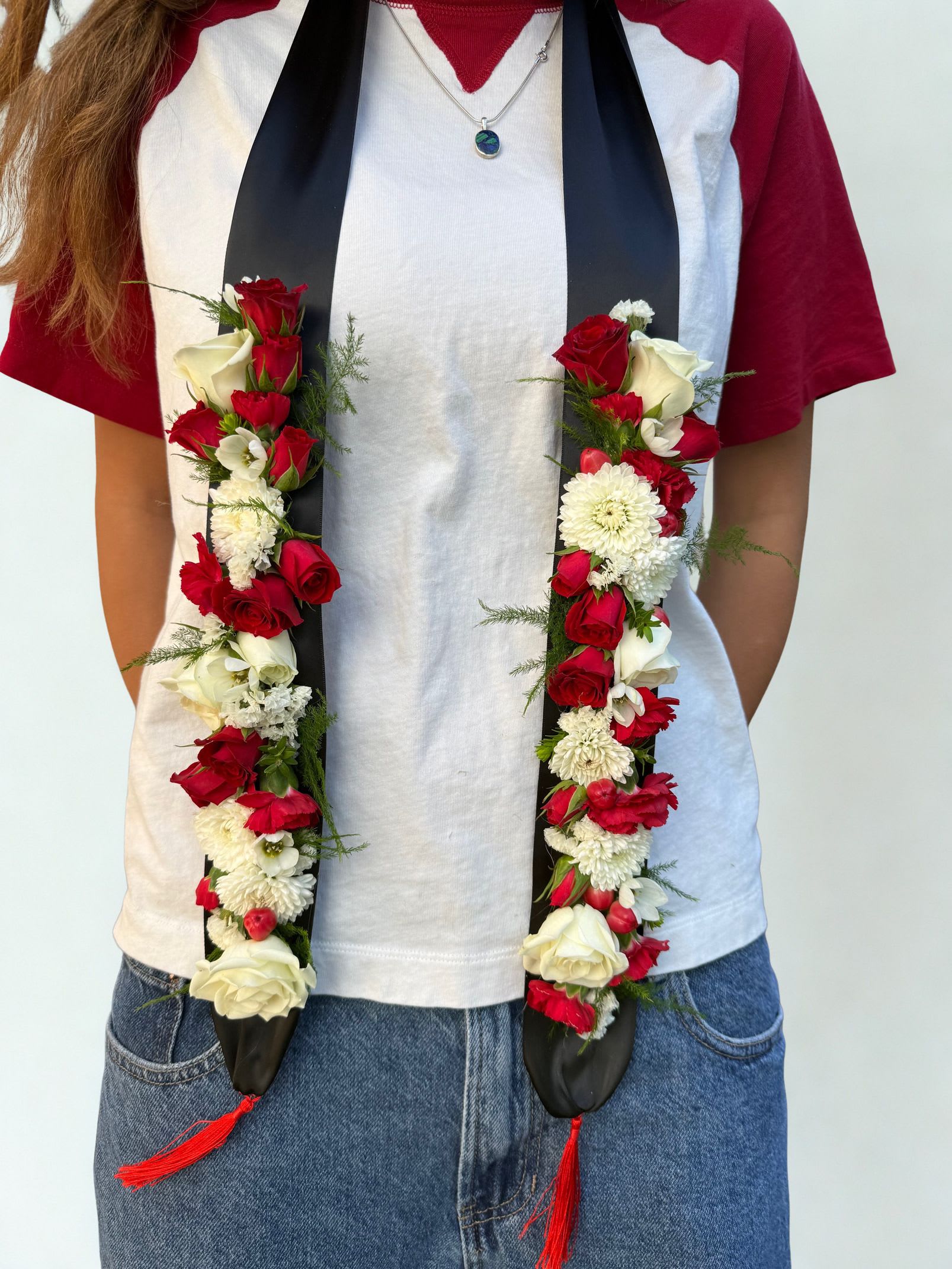 Graduation Swag - Celebrate graduation in style with our fresh floral graduation swag. Designed with a beautiful mix of seasonal blooms and greenery, this piece adds the perfect personalized touch to your graduation gown. Each swag is handcrafted by our designers and attached to a ribbon stole for an elegant look in photos and at the ceremony.  Please include your preferred flower colors in the special instructions at checkout so we can customize your swag to match your school colors or personal style. Flower varieties may vary based on seasonal availability.