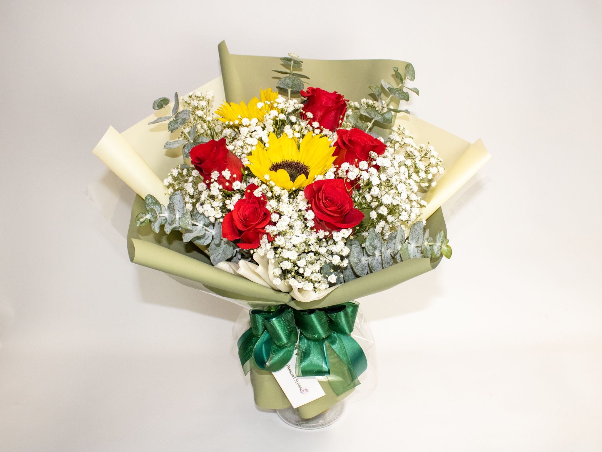 Bouquet of red roses and yellow sunflowers wrapped in green paper