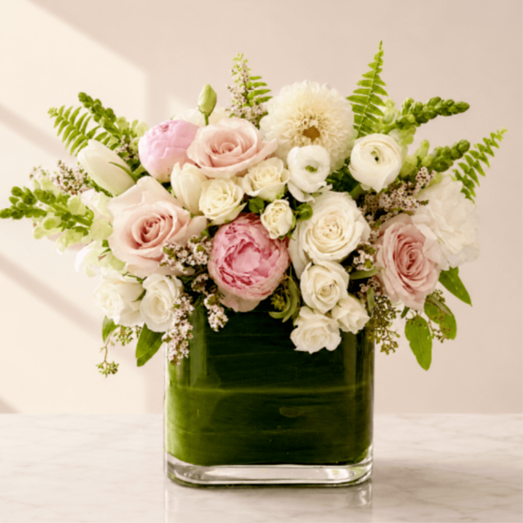 Pink and white roses with ranunculus in a square glass vase