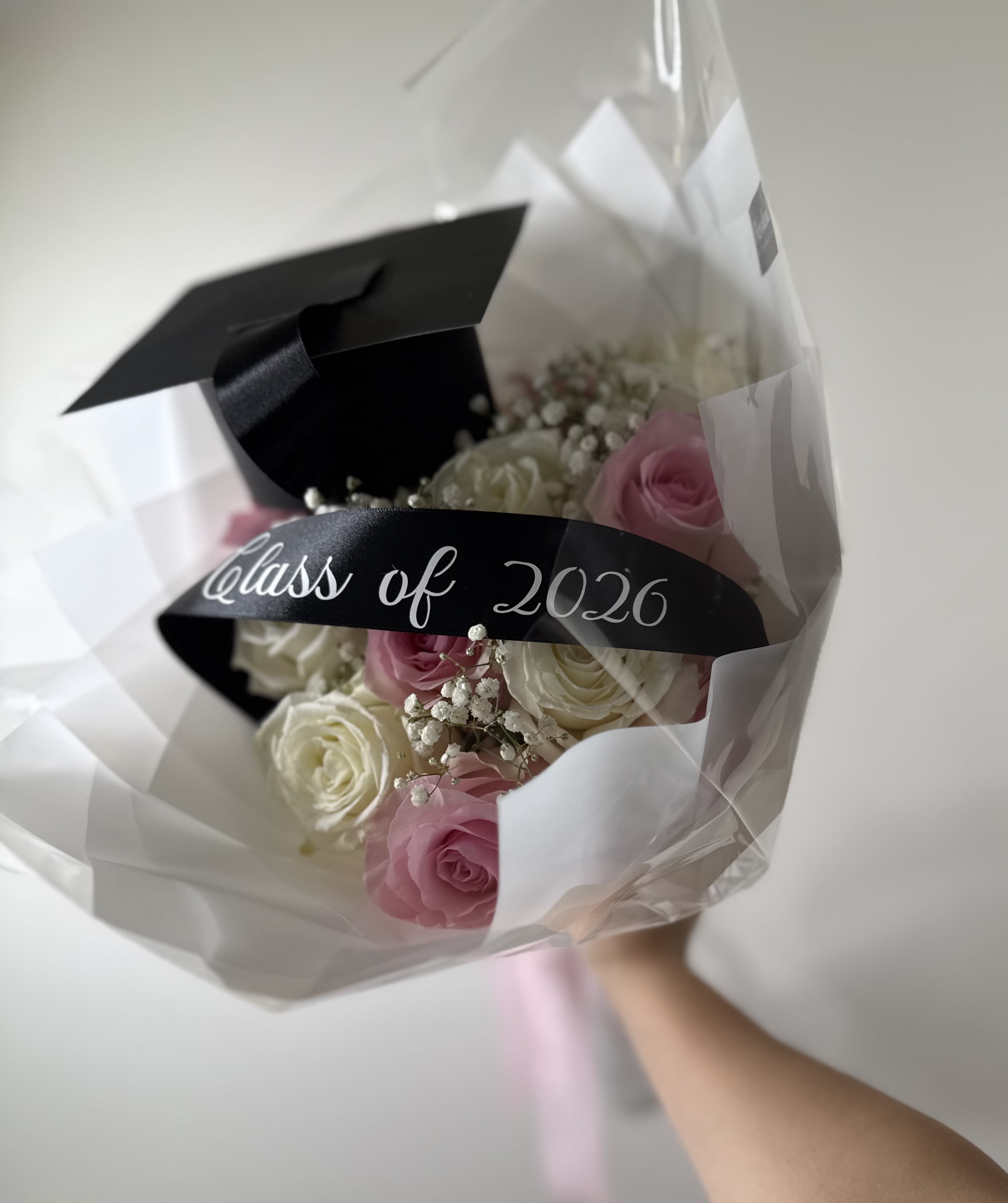 Classic Pink &amp; White Graduation Bouquet - A classic graduation arrangement with soft pink and white roses accented with baby’s breath and finished with our satin graduation ribbon.  Designed to feel clean, elegant, and unforgettable for graduation photos and celebrations.  • Fresh premium roses • Graduation cap detail included