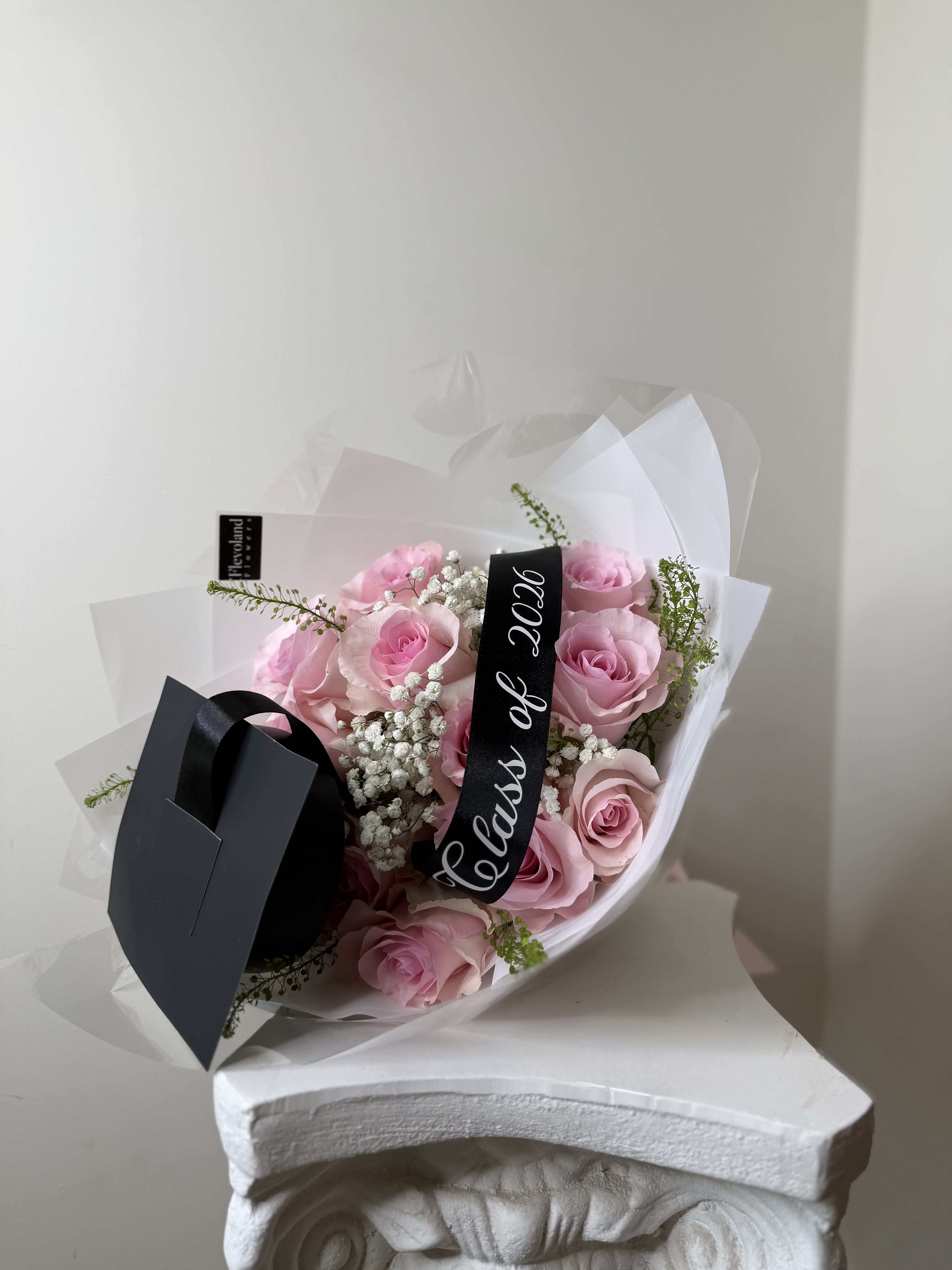 Blush Rose Graduation Bouquet - A full blush rose bouquet designed with soft pink roses, baby’s breath, fresh greenery, and graduation accents. Wrapped in white layered paper for a modern luxury presentation.  A beautiful keepsake bouquet for graduation day.