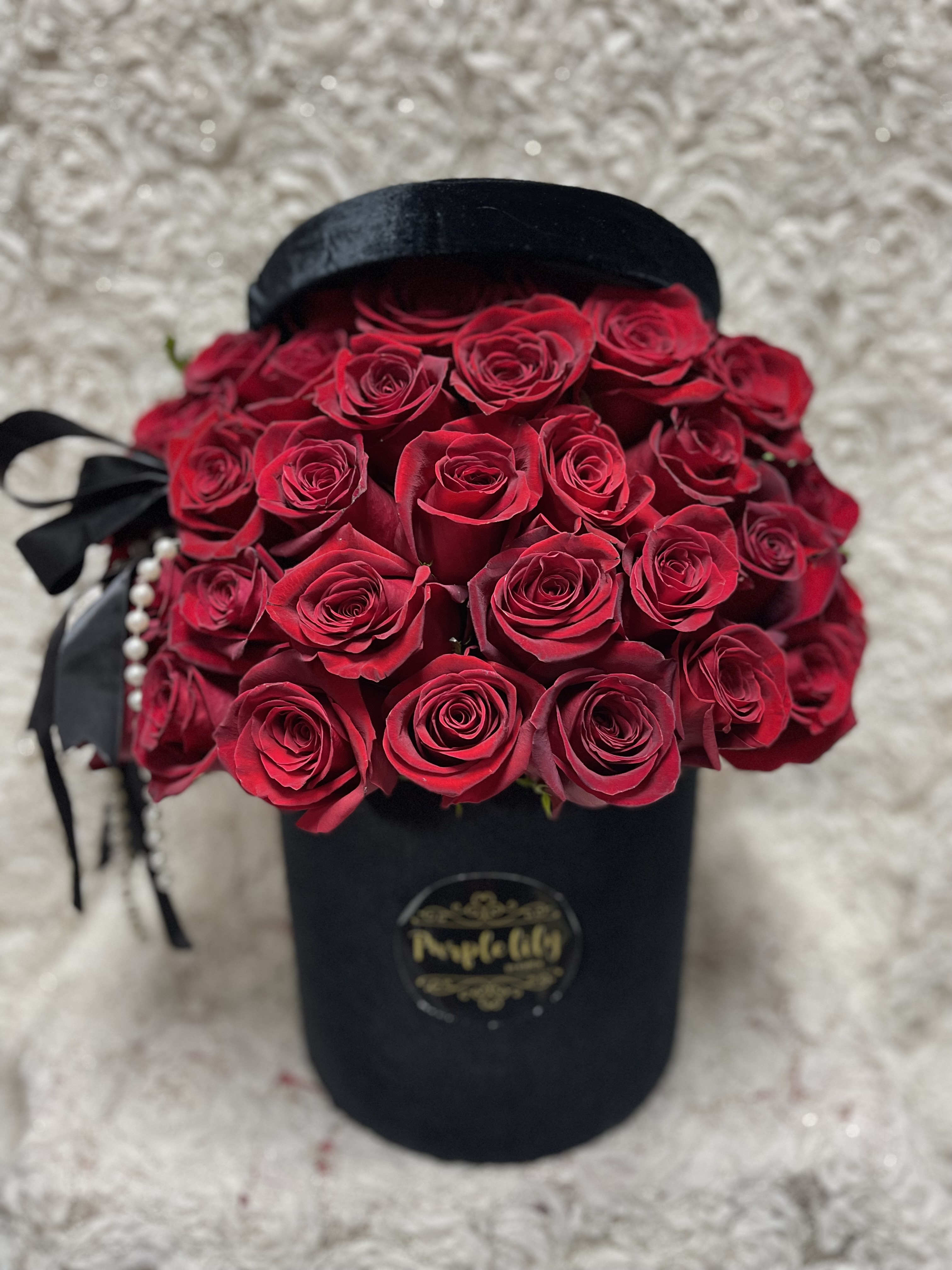 Bouquet of red roses in a black hat box with ribbon