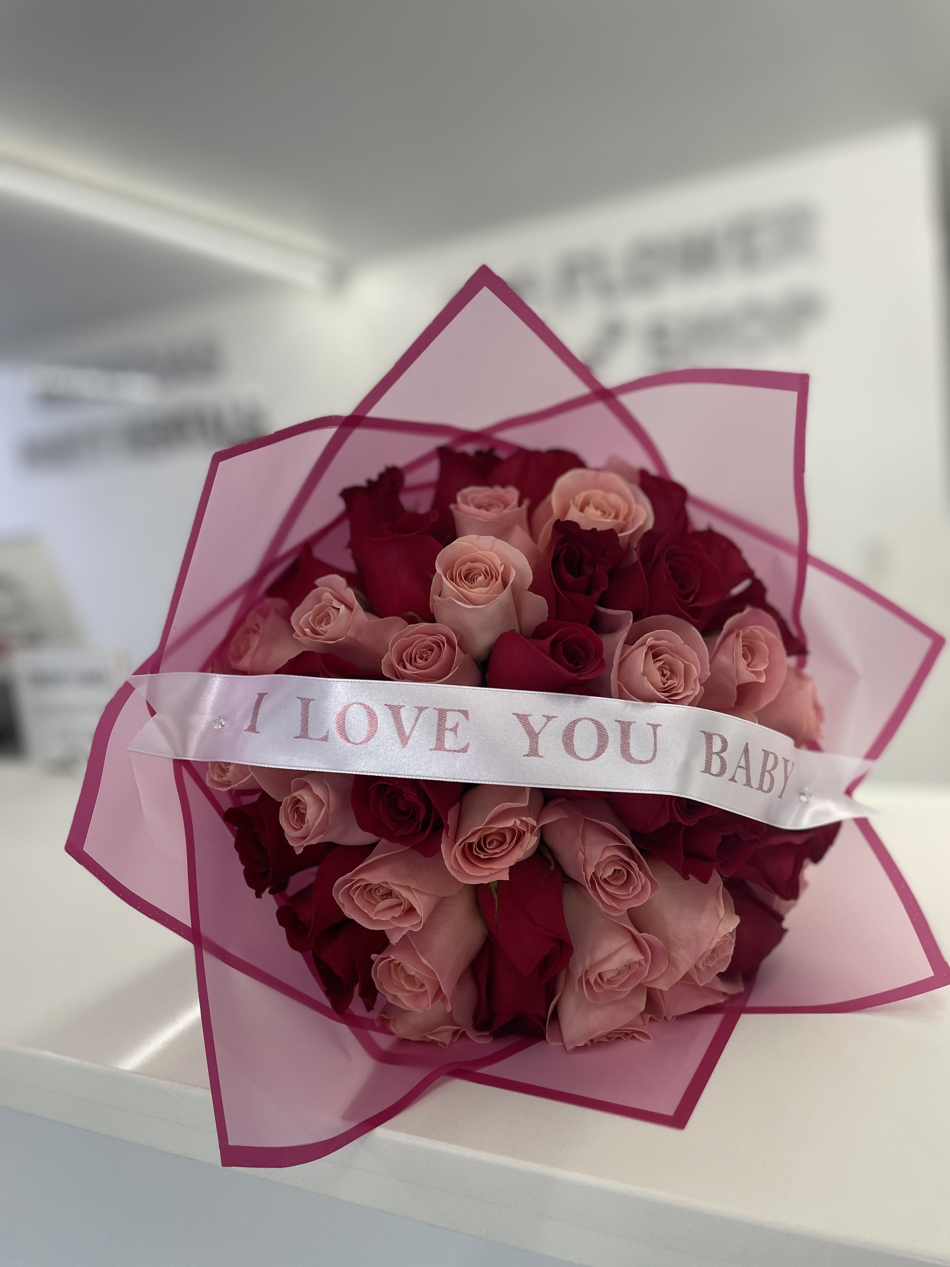 Bouquet of pink and red roses wrapped in pink paper with a ribbon