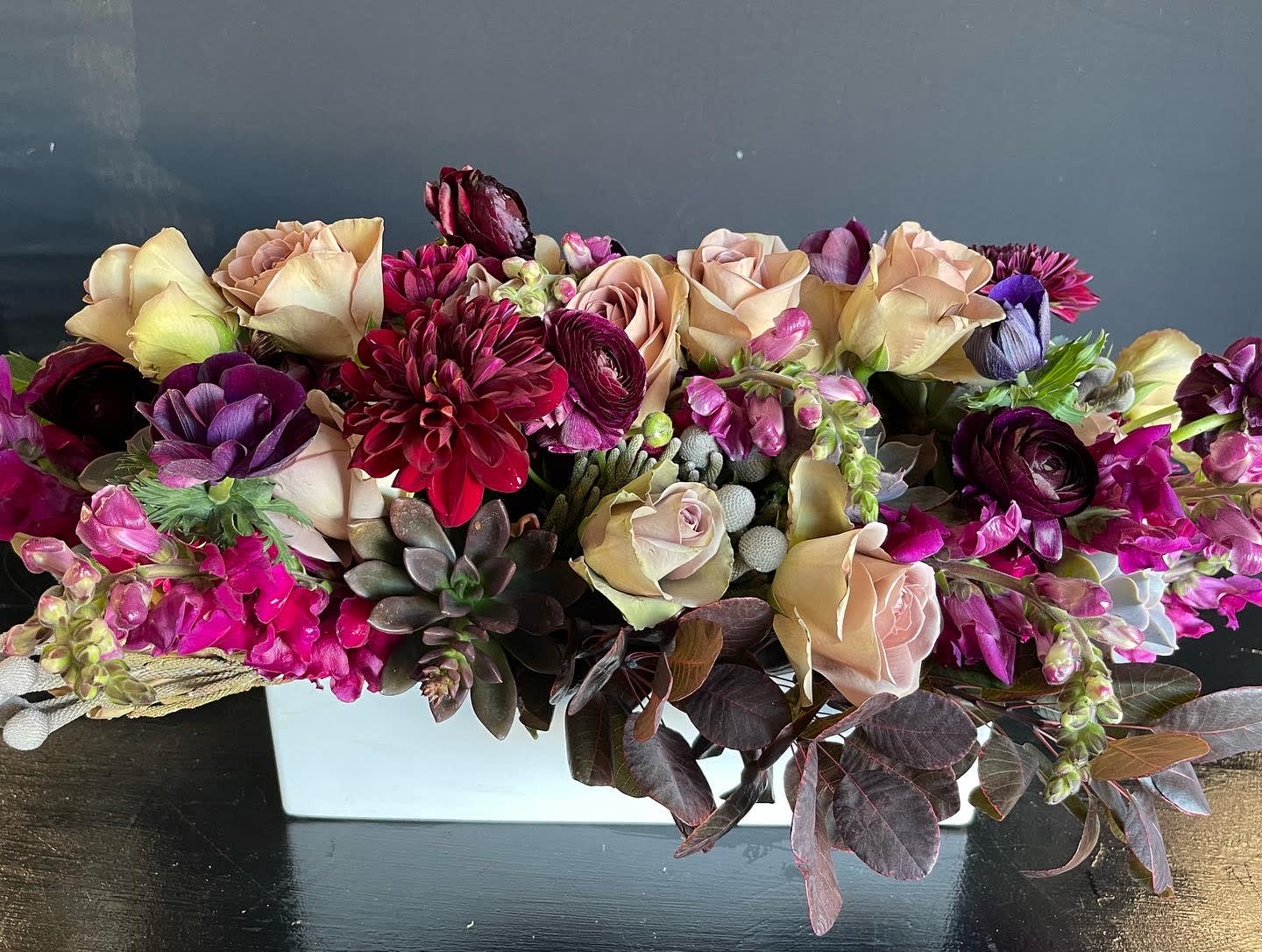 Low and long stunning centerpiece.  - We've taken a white ceramic stunning long  vessel and filled it with dahlias, scabiosas, succulents, artichokes, kale, silver brunia, dusty miller, roses and anemones. Simply the best! We aim for recipient to fall in love and tell you this is simple the best flowers they've ever received.   When you order online you will receive several emails until order has been completed and delivered by the designer who put it together.  We are more than just flowers; we are an experience you will love. 