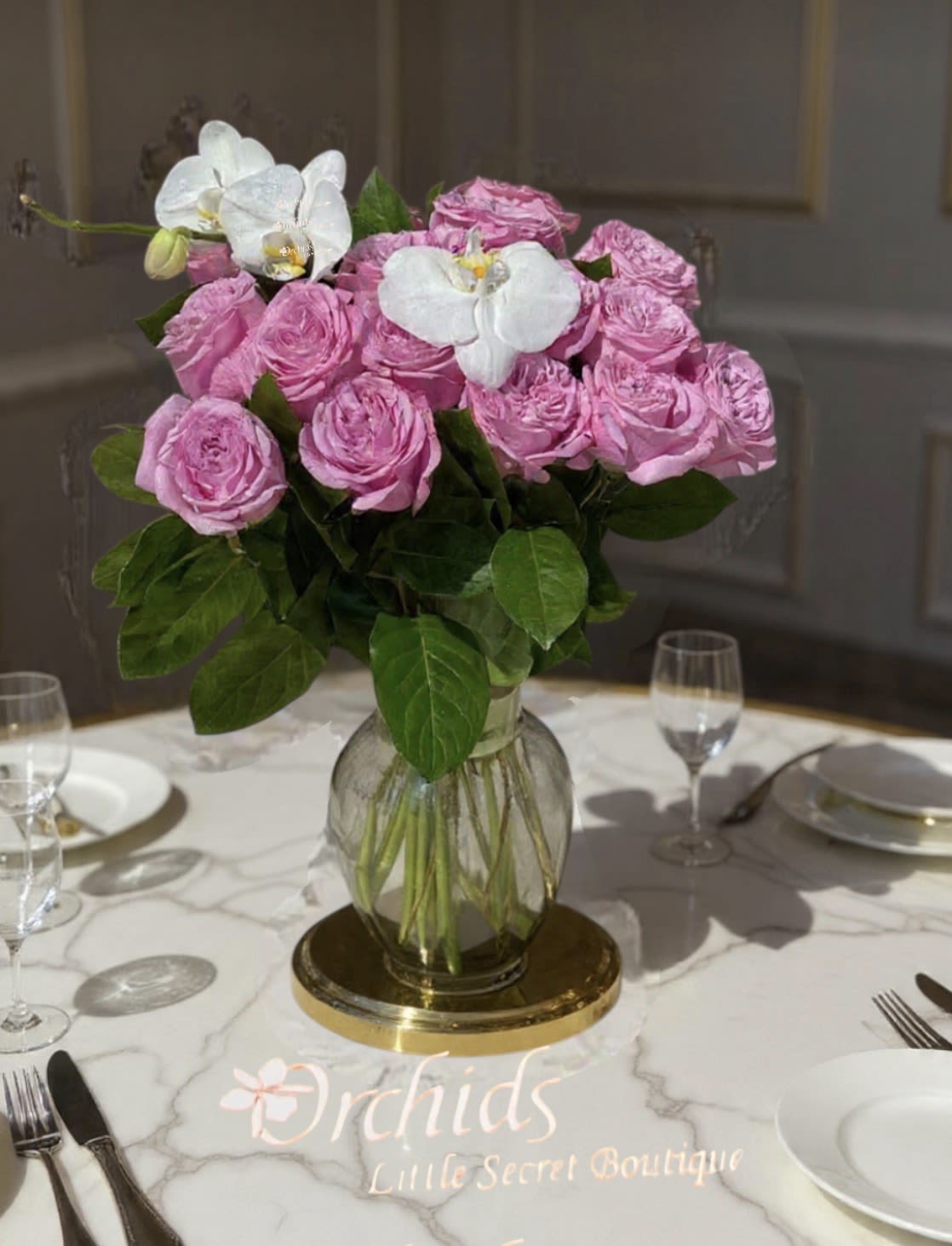 Pink roses and white orchids in a glass vase on a table