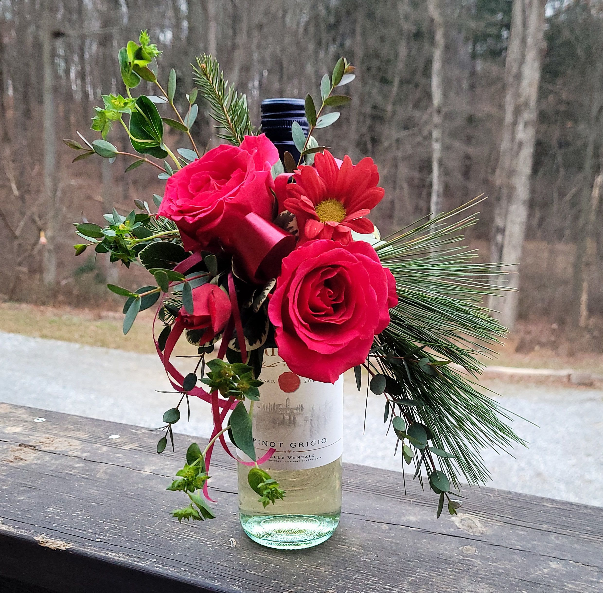 Pink roses and a red daisy in a wine bottle vase