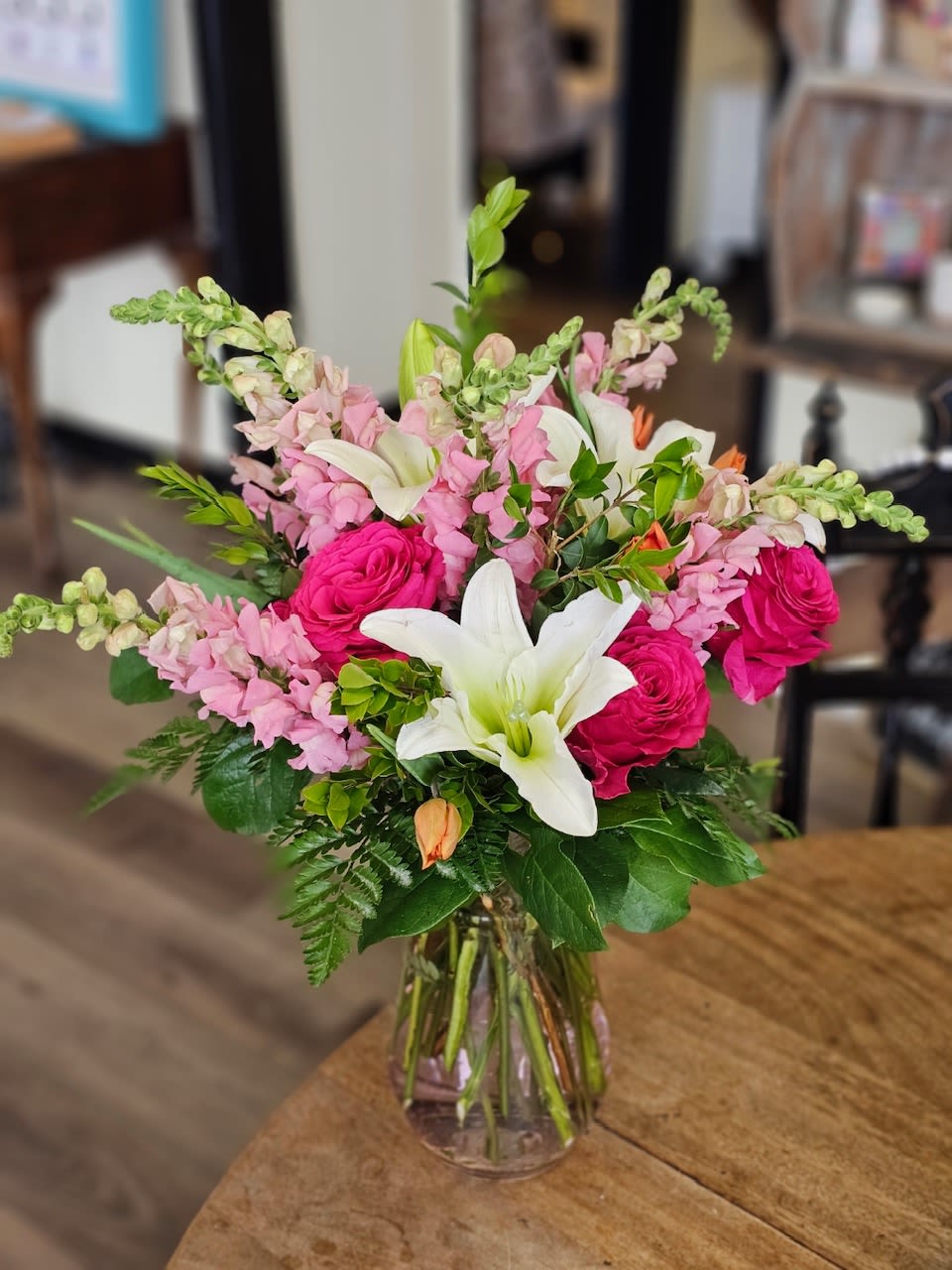 Bouquet of pink roses, white lilies, and pink snapdragons in a glass vase