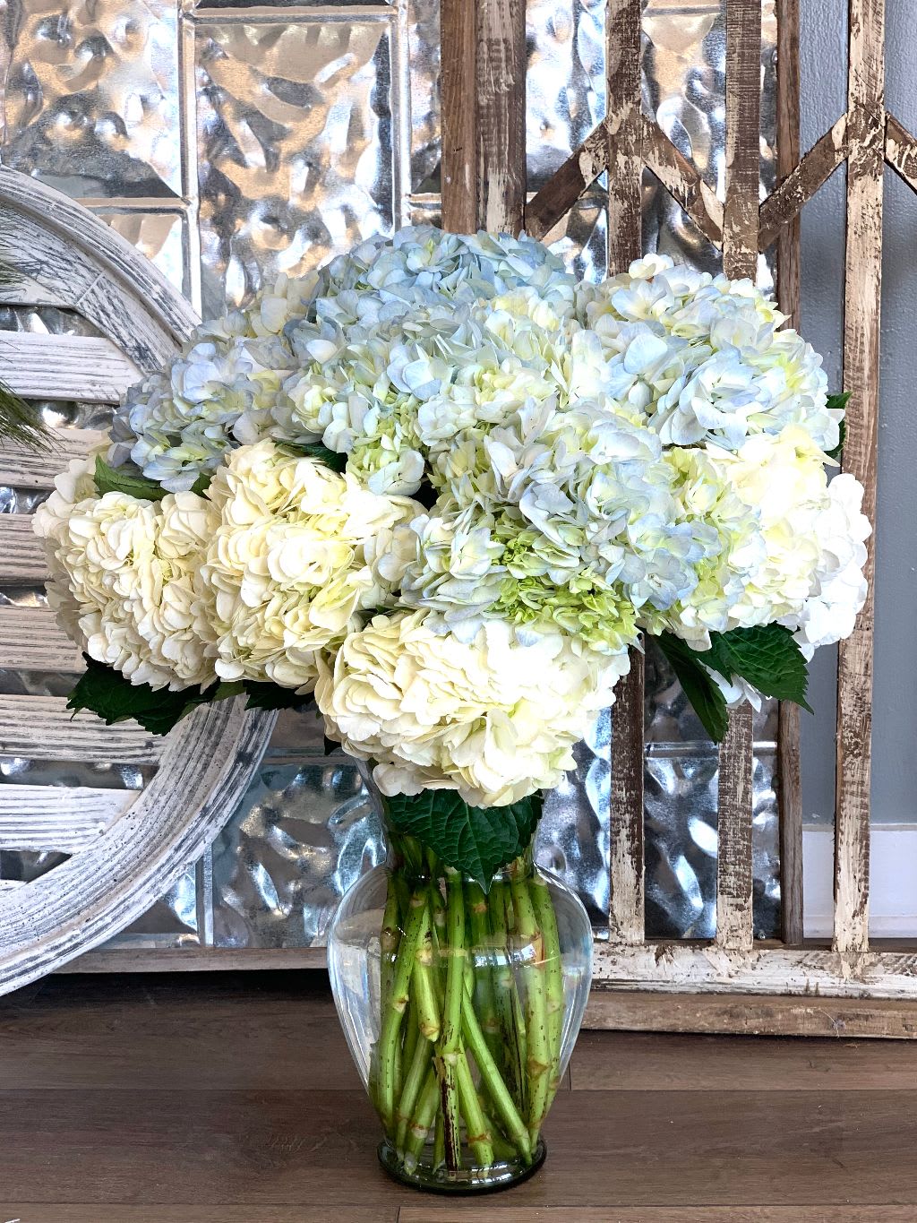 White and pale blue hydrangea bouquet in a clear glass vase
