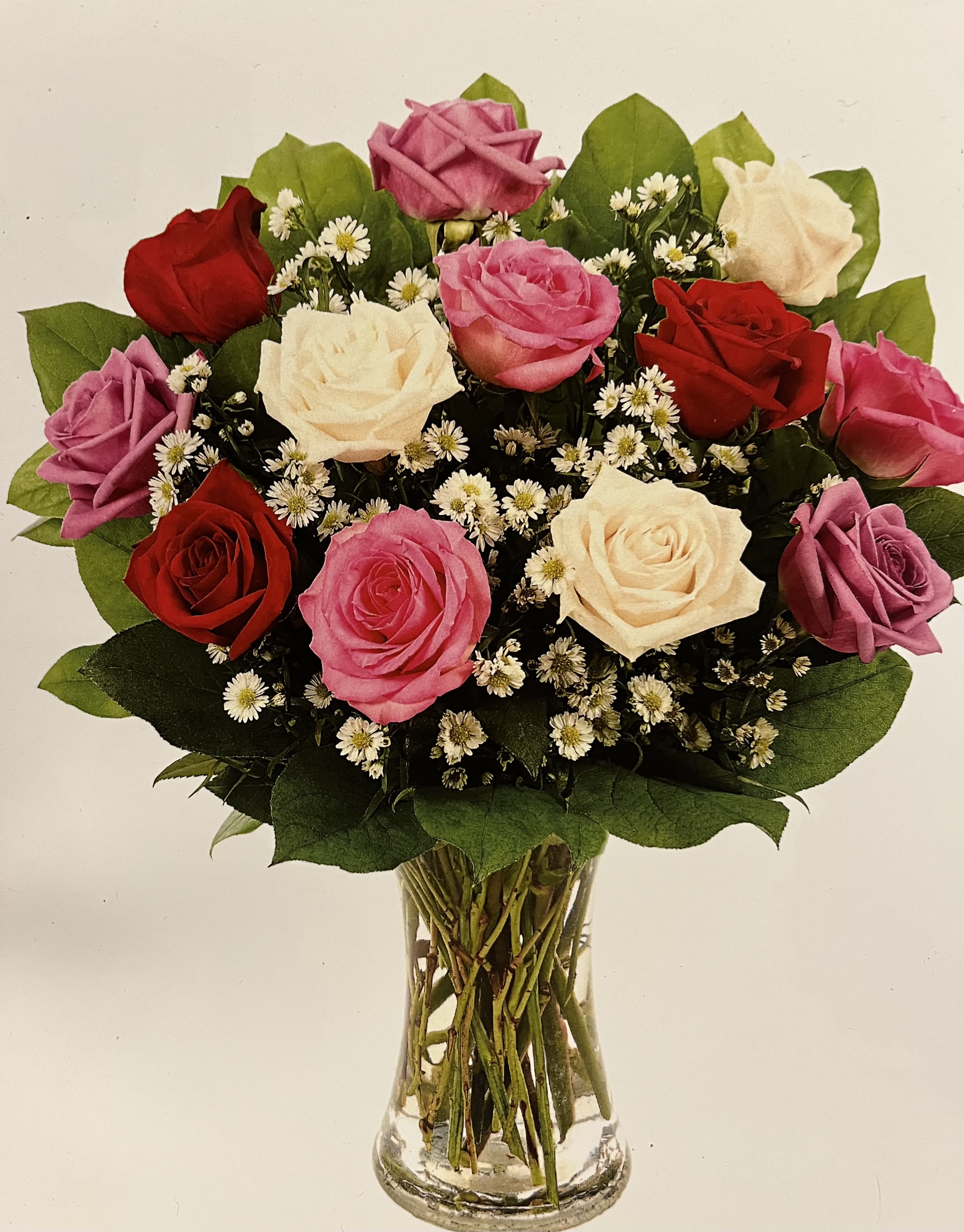 Mixed roses in pink, red, and white arranged in a clear glass vase