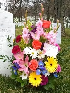 Colorful funeral flower arrangement placed beside a gravestone