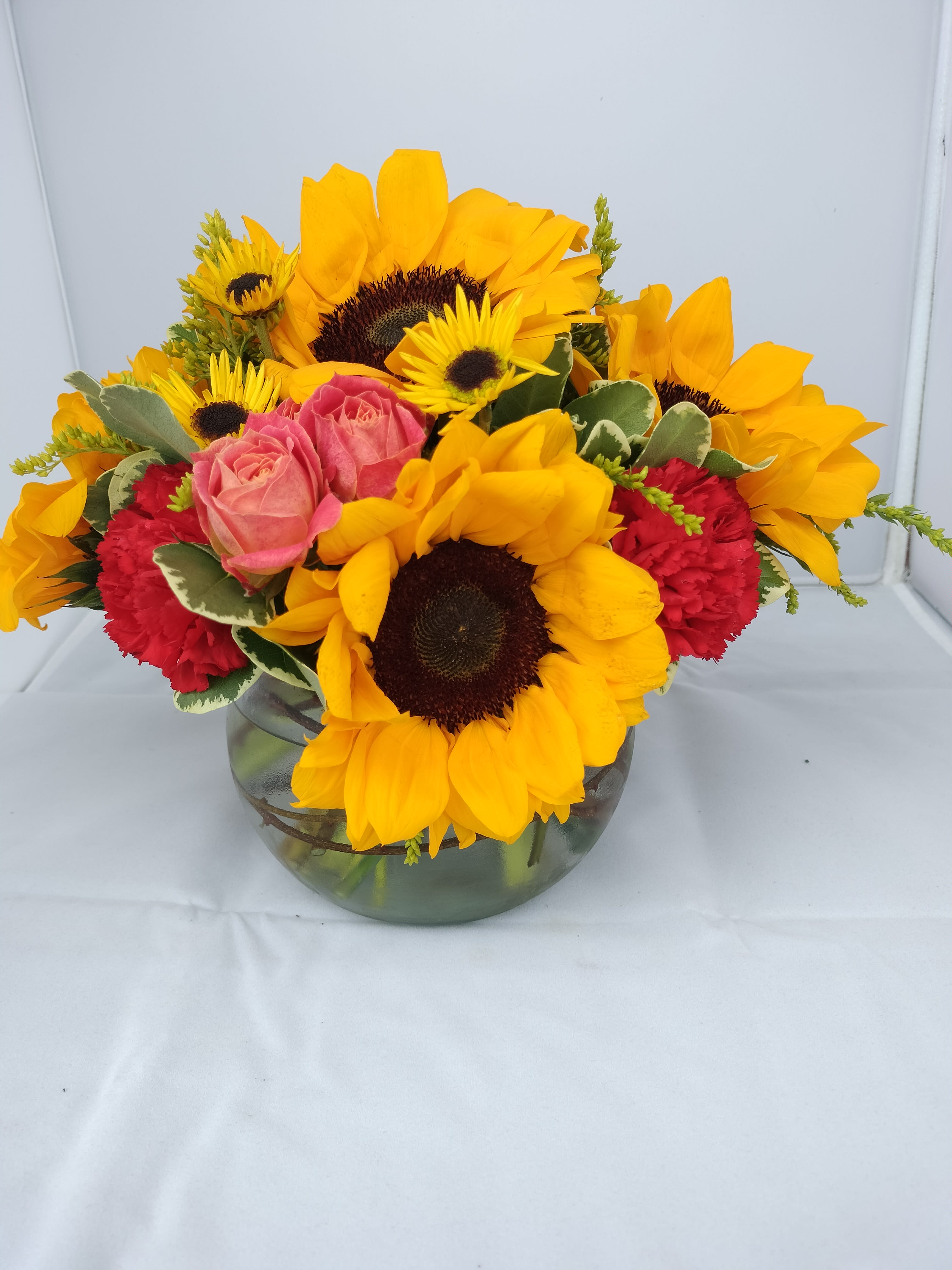 Sunflowers and pink roses arranged in a glass vase