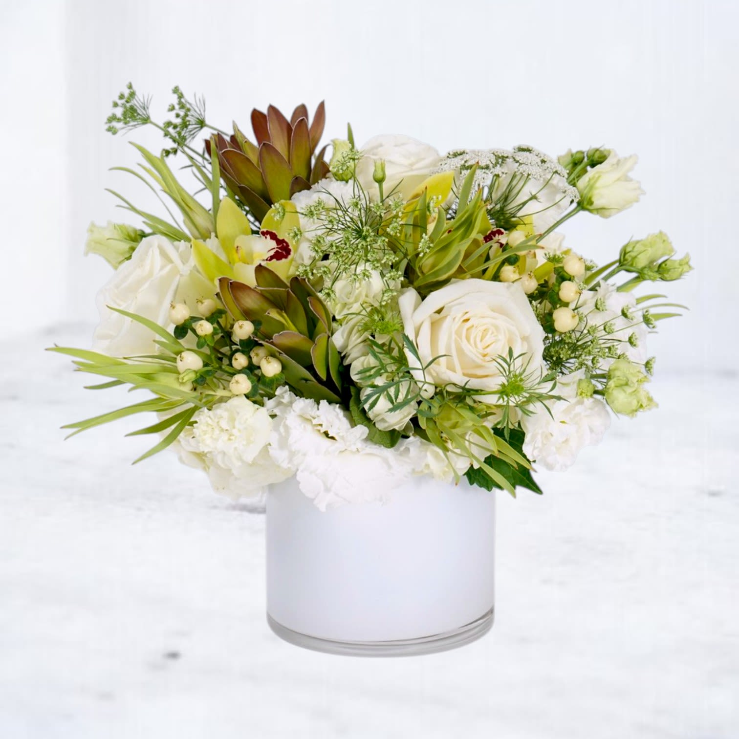 Wildlight - Wildlight is a modern white and green floral arrangement designed with premium white roses, lisianthus, orchids, carnations, leucadendron, Queen Anne’s lace, hypericum berries, and seasonal blooms arranged in a sleek white vessel. Featuring layered botanical textures, airy movement, and soft natural tones, this design blends refined garden florals with sculptural greenery for a fresh contemporary statement.  Perfect for sympathy flowers, thank-you gifts, birthdays, celebrations, or elegant everyday flower delivery, Wildlight brings together delicate white blooms, organic greenery, and modern floral artistry in a design that feels serene, textural, and effortlessly elevated.  Designed with premium seasonal flowers and natural movement for fullness, softness, and an artistic garden-inspired presentation.  Available for same-day flower delivery in Magnolia, The Woodlands, Montgomery, Conroe, Spring, Tomball, and surrounding Houston communities.