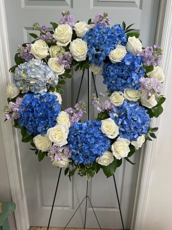 Standing Spray Wreath - Elegant, serene blooms arranged to honor a cherished life. Wreath  Contains Assorted Hydrangea , White Roses , Lavender Stock,  Fancy Greens