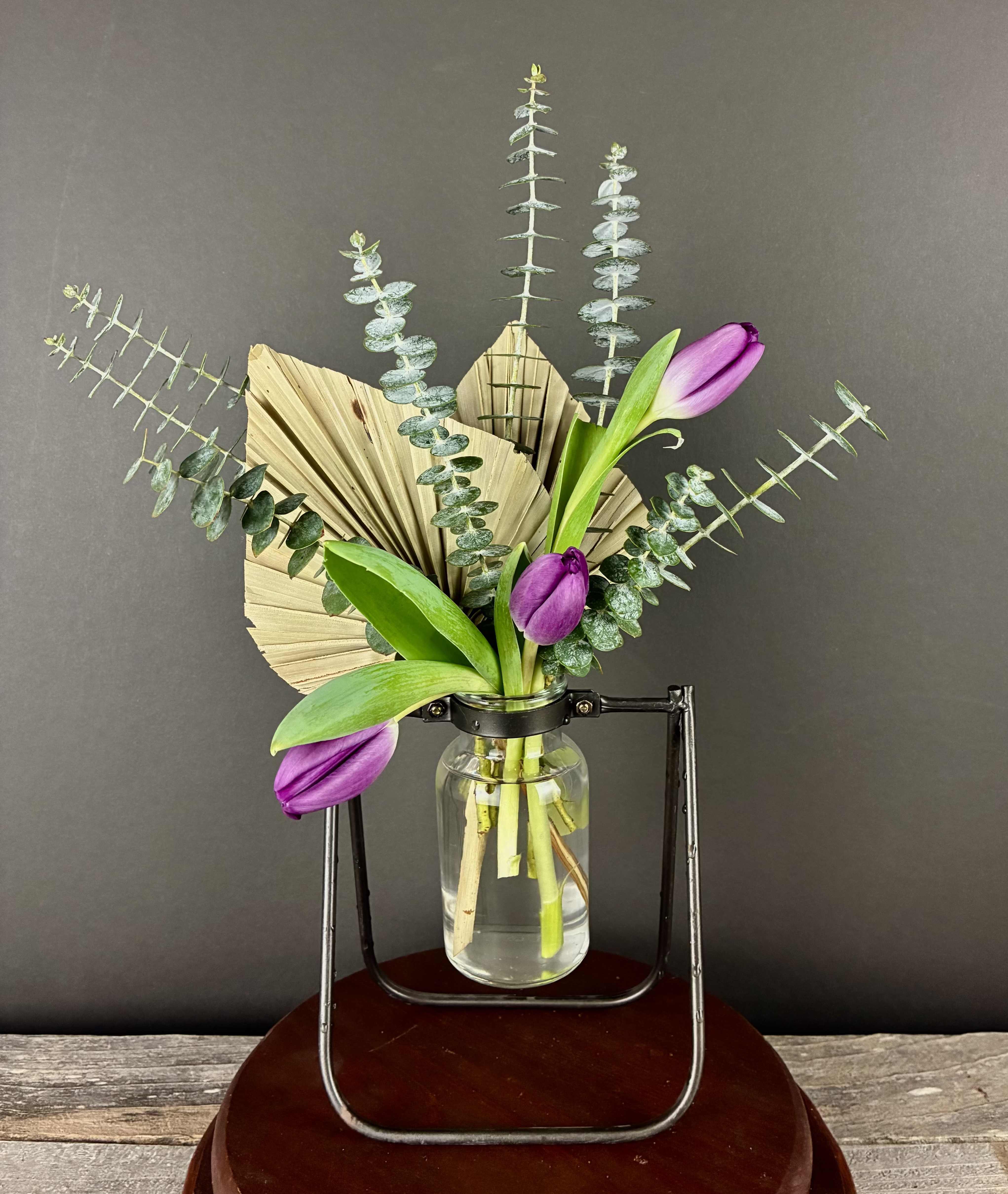 Purple tulips in a glass jar with dried palm and eucalyptus