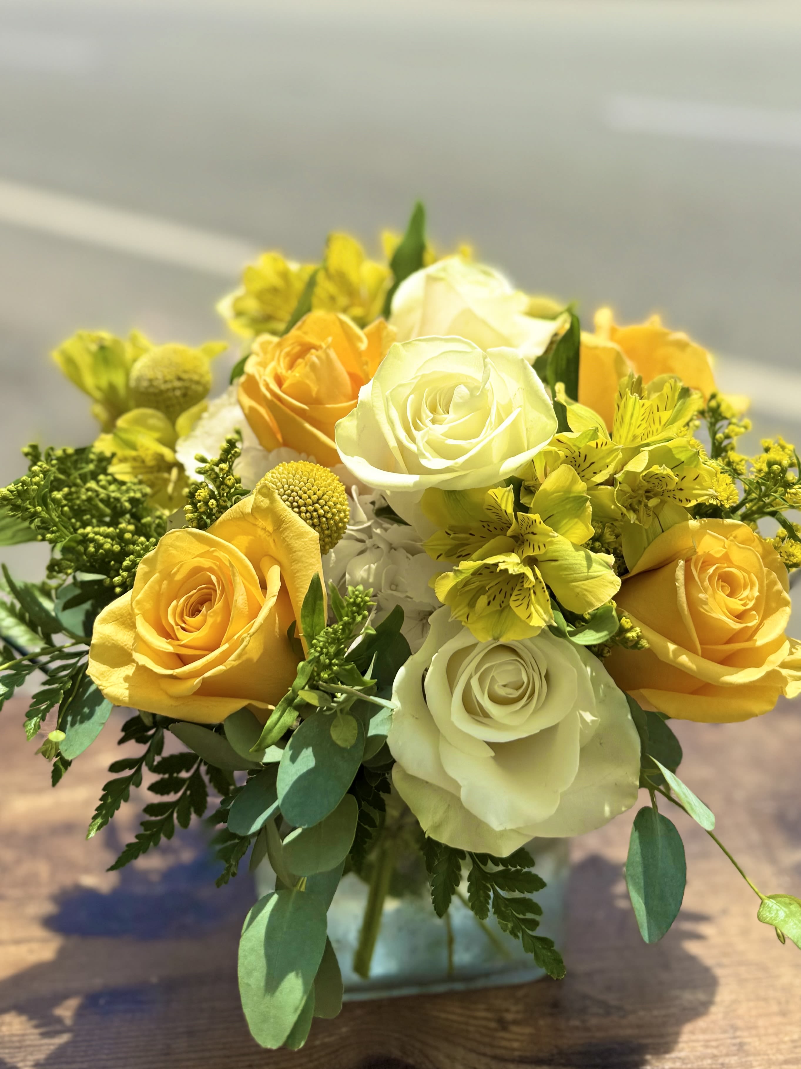 Yellow and white roses with yellow alstroemeria in a glass vase