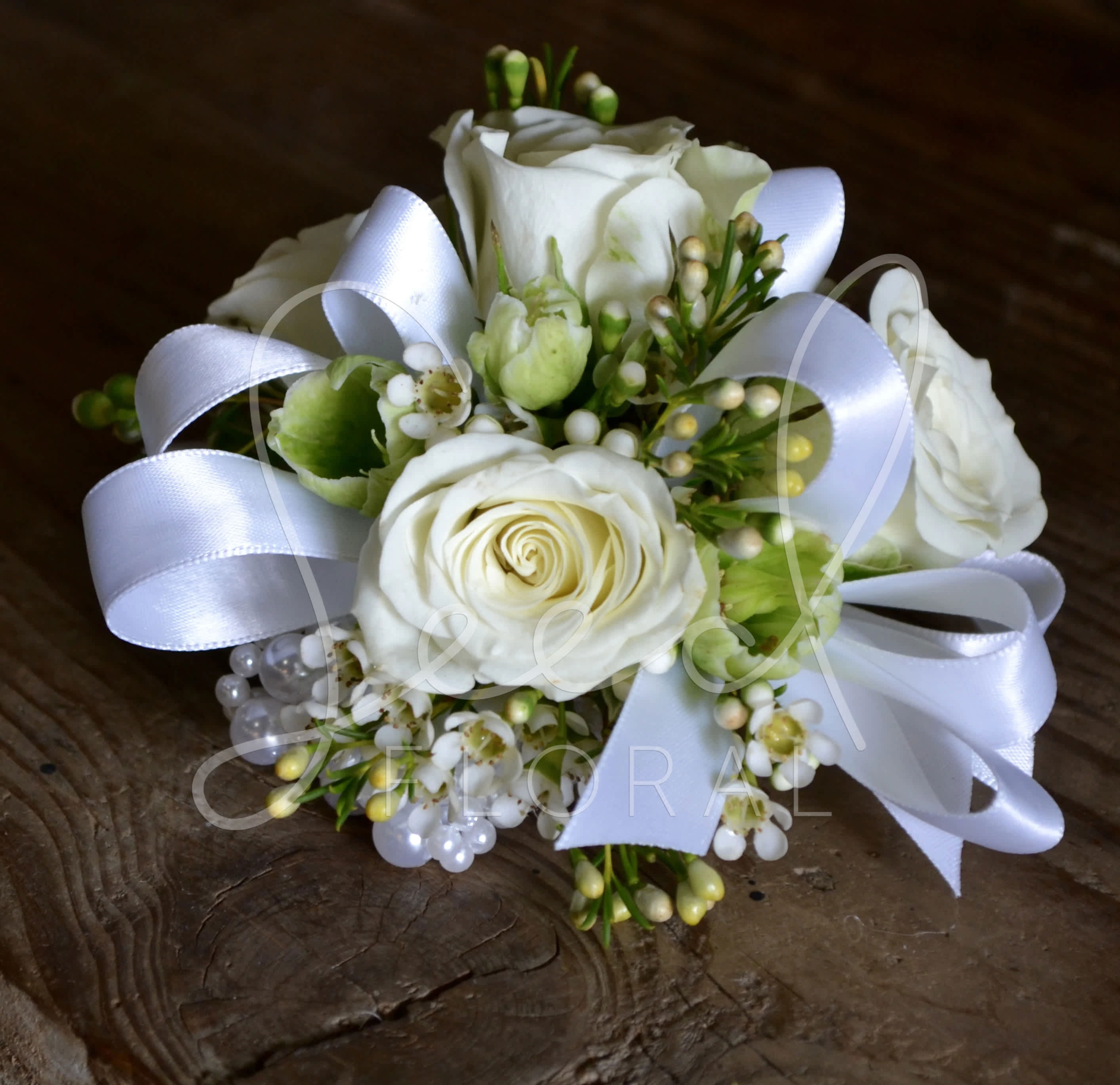 White Spray Rose Corsage - Ivory Pearl Wristlet Corsage with white spray roses, wax flower, and greens with ribbon detail.