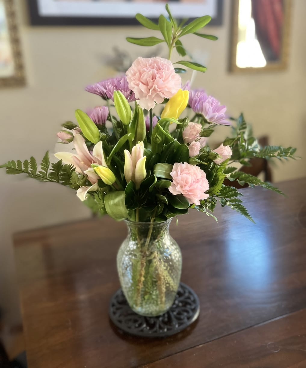 Mixed bouquet of pink and purple flowers in a glass vase