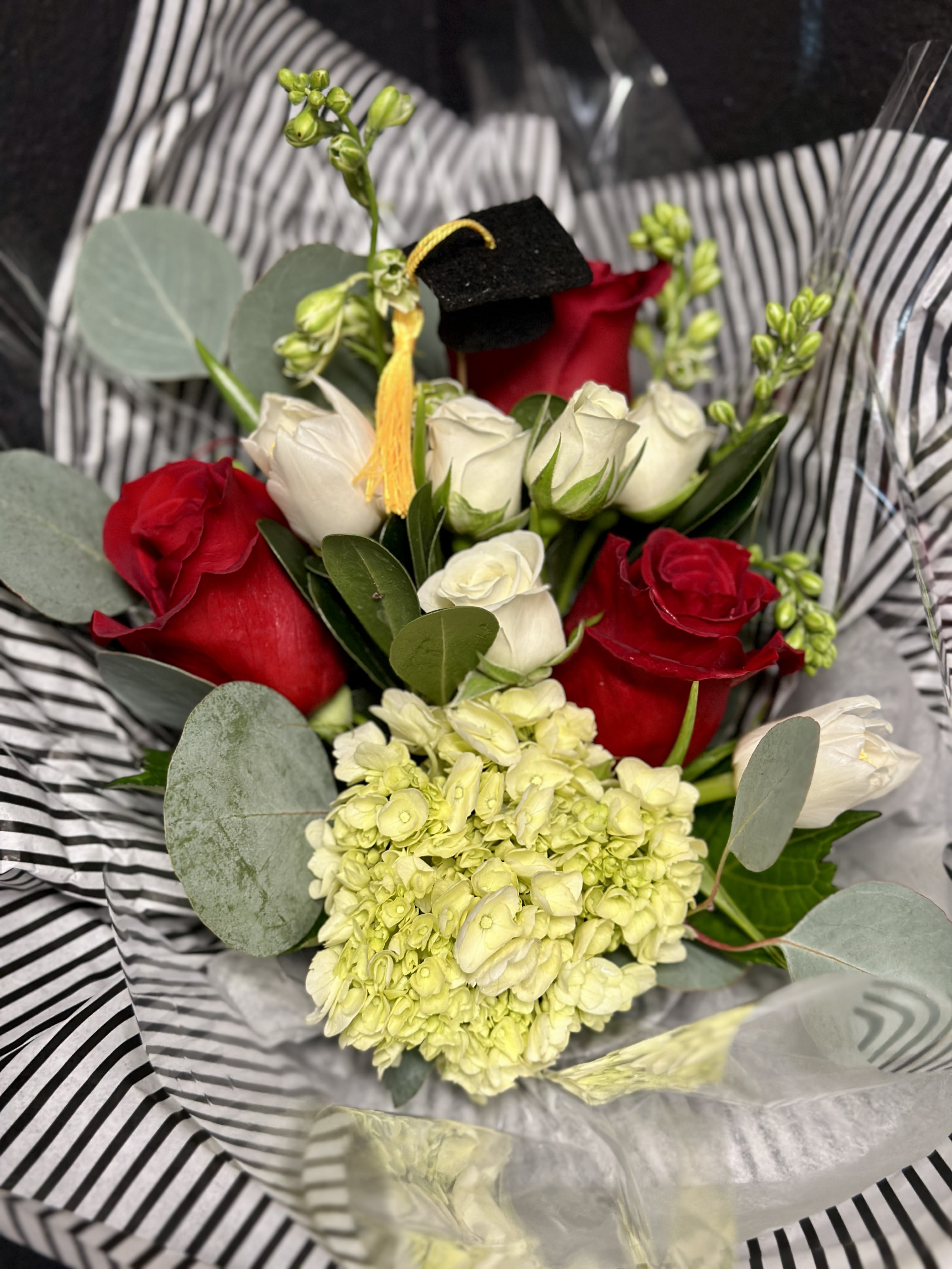 Graduation Paper Wrap- Red &amp; White  - Celebrate your LT Grad with a pretty paper wrapped bouquet in Red &amp; White. Stems and a super cute mini graduation cap pick are wrapped in our fancy tissue papers &amp; placed on a temporary water source. Give us a call if you're hoping for another color option. 