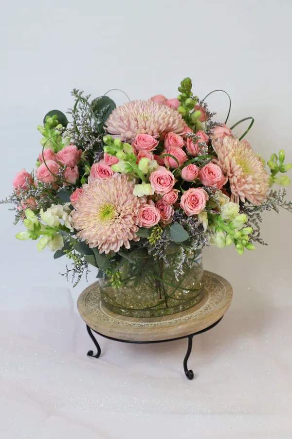 Pink roses and pale chrysanthemums arranged in a glass vase