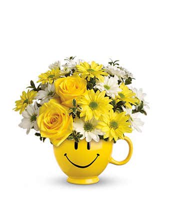 Yellow smiley-face mug filled with yellow and white flowers