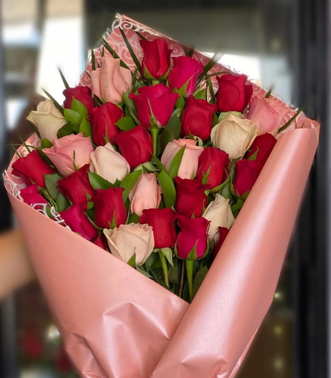 Bouquet of red and blush roses wrapped in pink paper